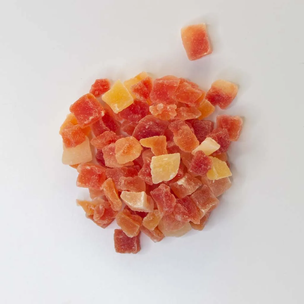 Traina® Dried Papaya, Sweetened, -diced 8-10mm. Small pile of dried fruit on white background.