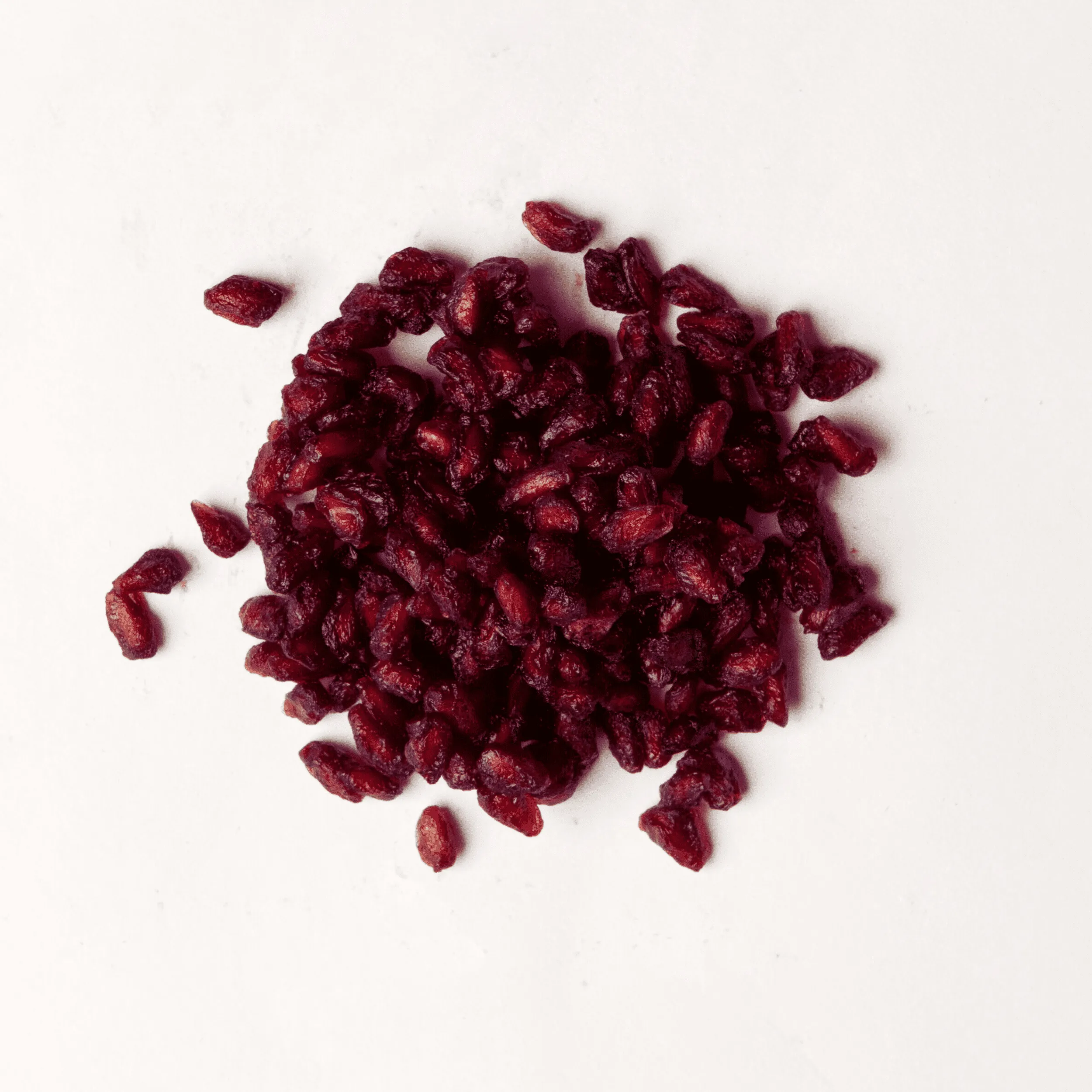 Traina® Dried Pomegranate, Sweetened - Arils,. Small pile of dried fruit on white background.