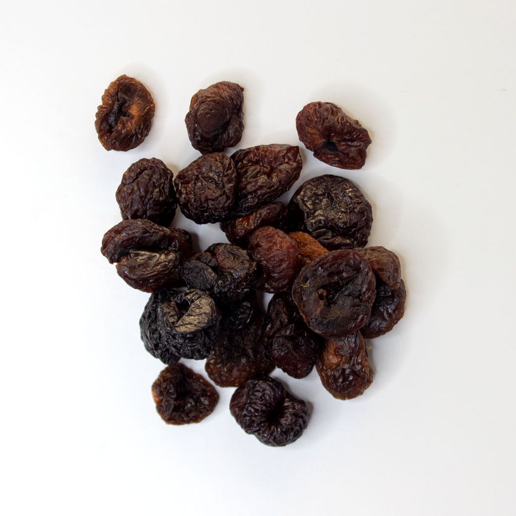 Traina® Organic California Sun Dried Rainer Cherries, pitted, whole - small pile of sun dried fruit on white background.