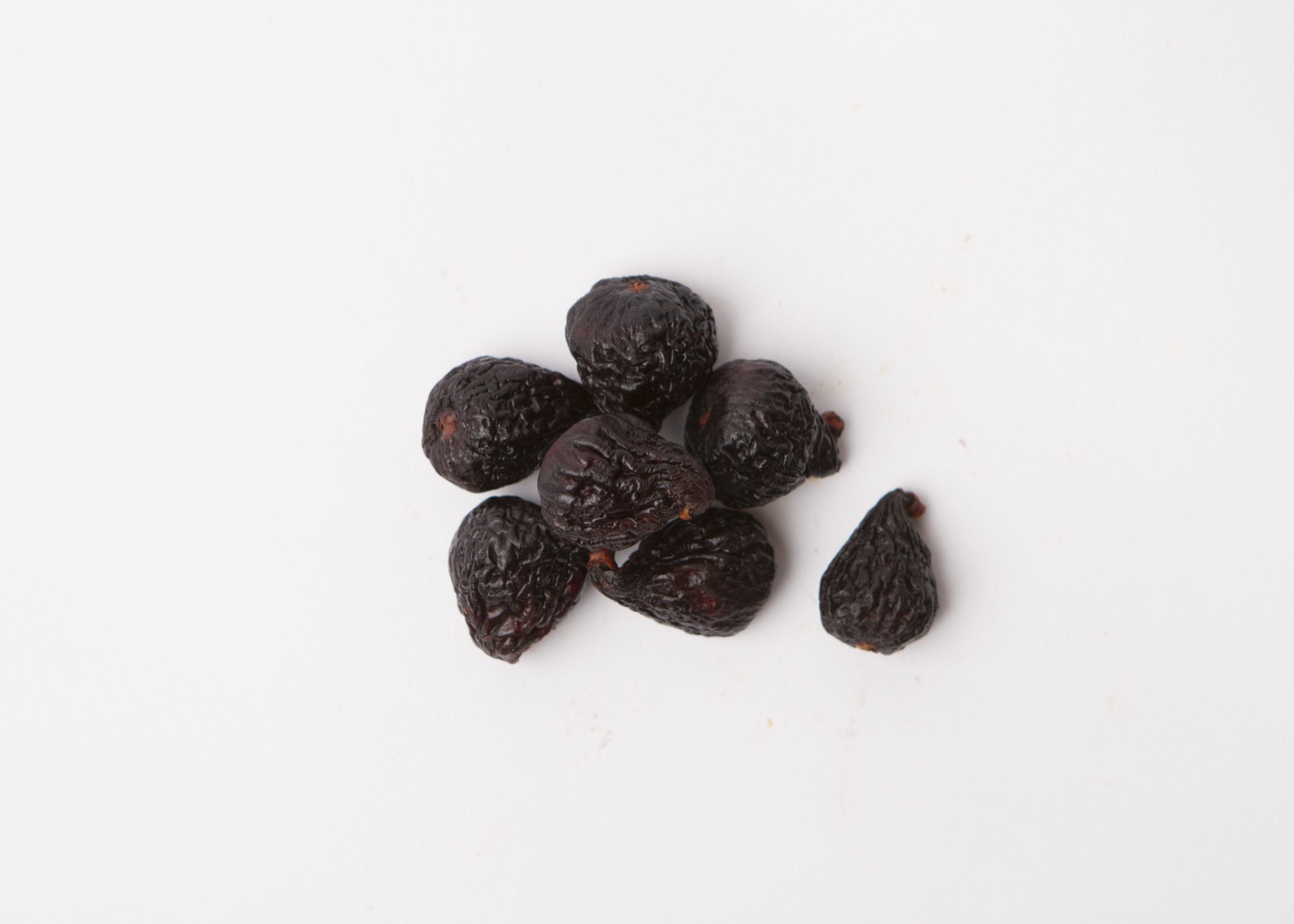 Traina® California Dried Mission Figs, whole - small pile of dried fruit on white background.