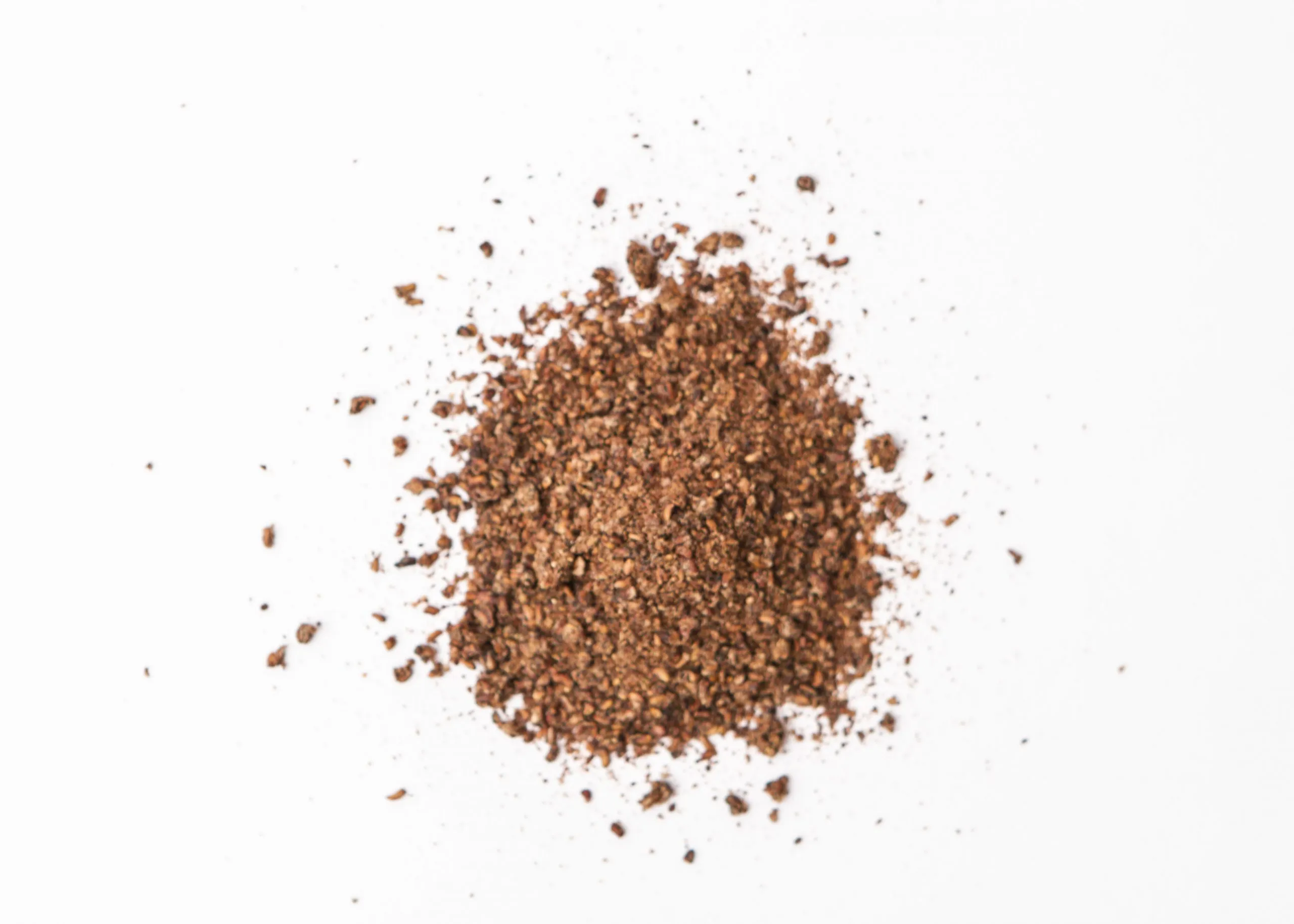 Traina® Dried Raspberry, granules - small pile of sun dried fruit on white background.