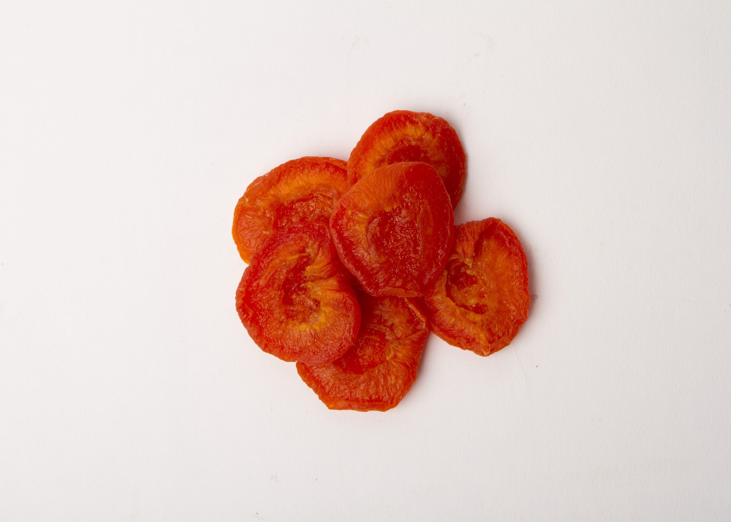 Traina® California Sun Dried Ruby Royal Apricots, Extra Fancy, halves - small pile of sun dried fruit on white background.