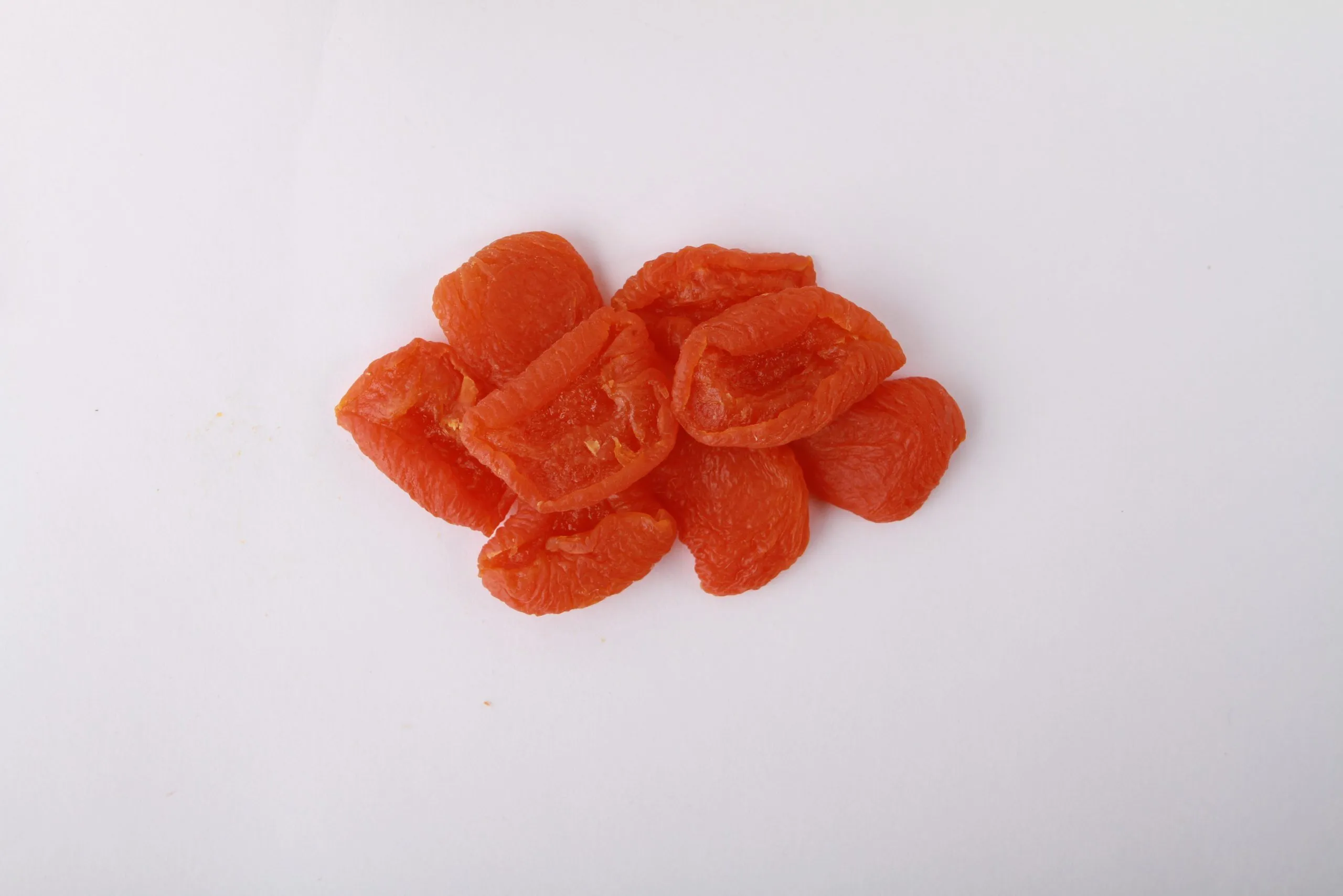 Traina® California Sun Dried Ruby Royal Apricots, Extra Choice, halves - small pile of sun dried fruit on white background.