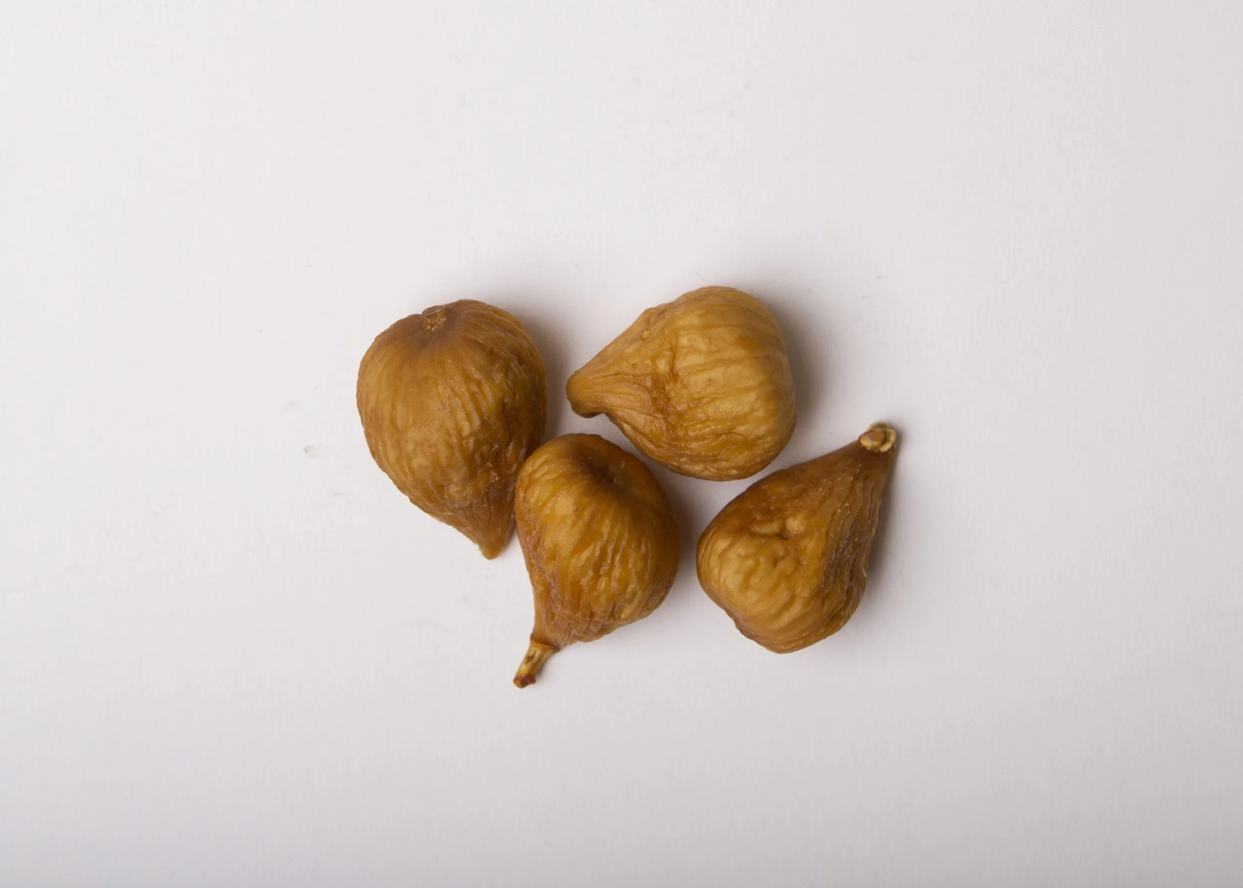 Traina® California Dried Sierra Figs, whole- small pile of dried fruit on white background.