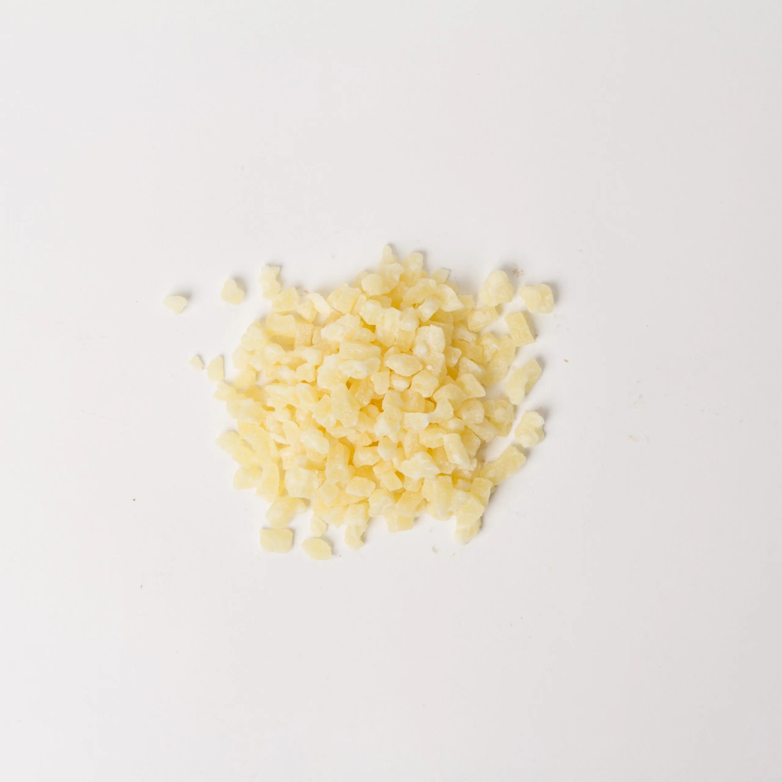 Traina® Dried Pineapple Sweetened, diced 3-5mm - small pile of dried fruit on white background.