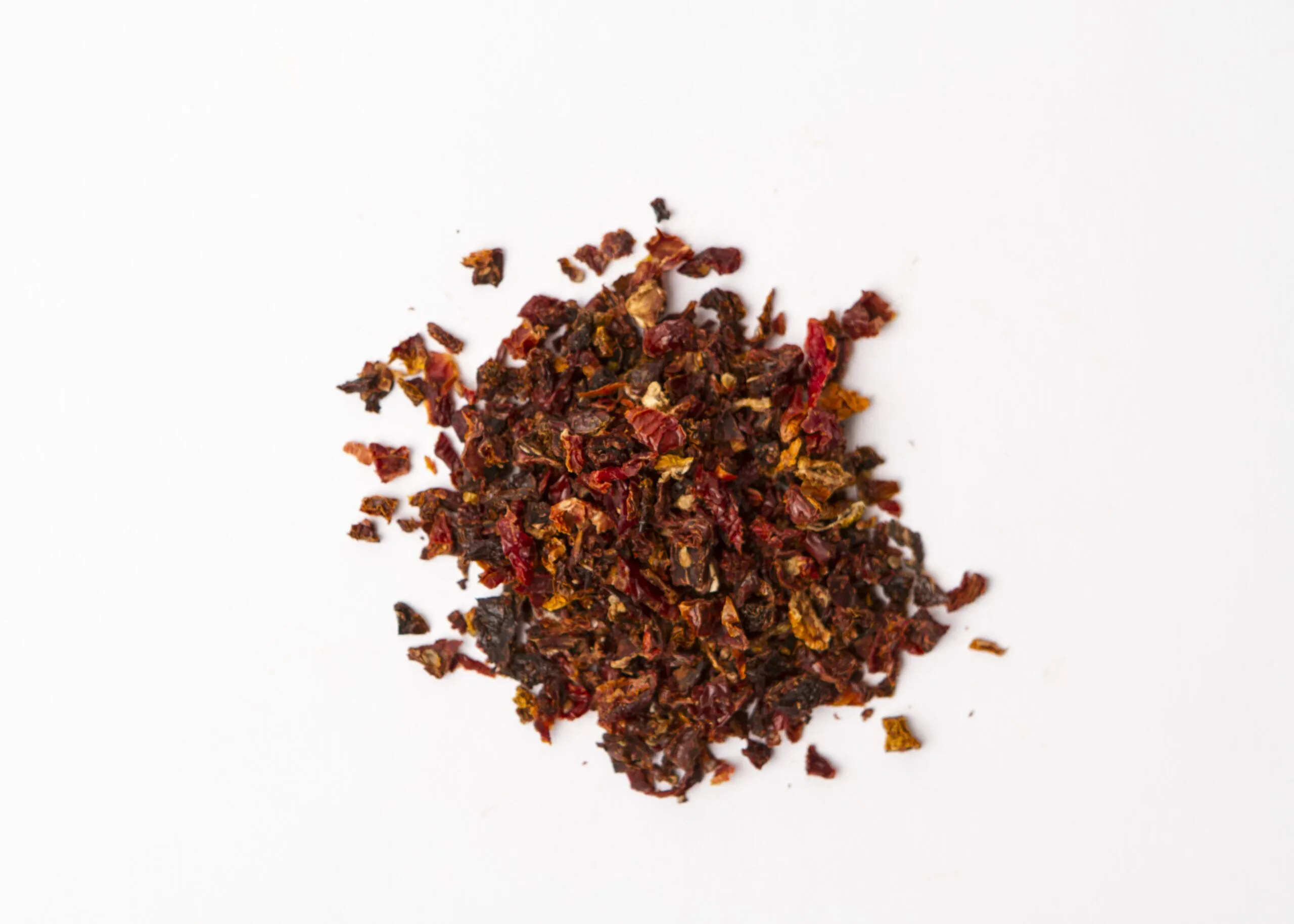 Natural California Sun Dried Tomatoes, no salt, double-diced - small pile of sun dried tomatoes on white background.