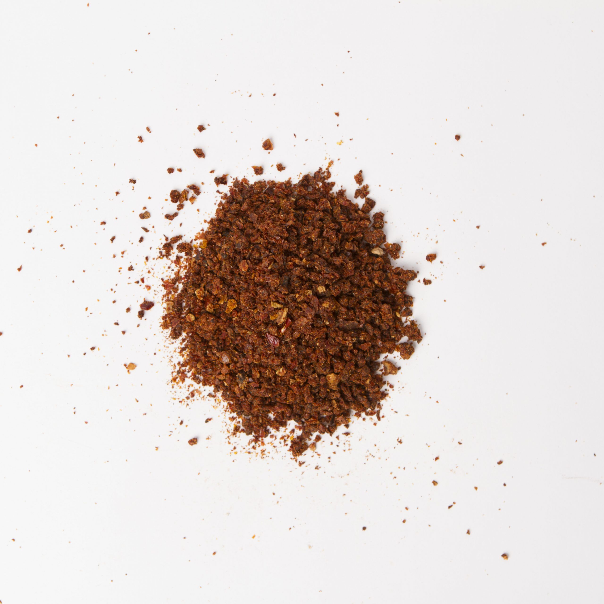 Natural California Sun Dried Tomatoes, no salt, triple-diced - small pile of sun dried tomatoes on white background.