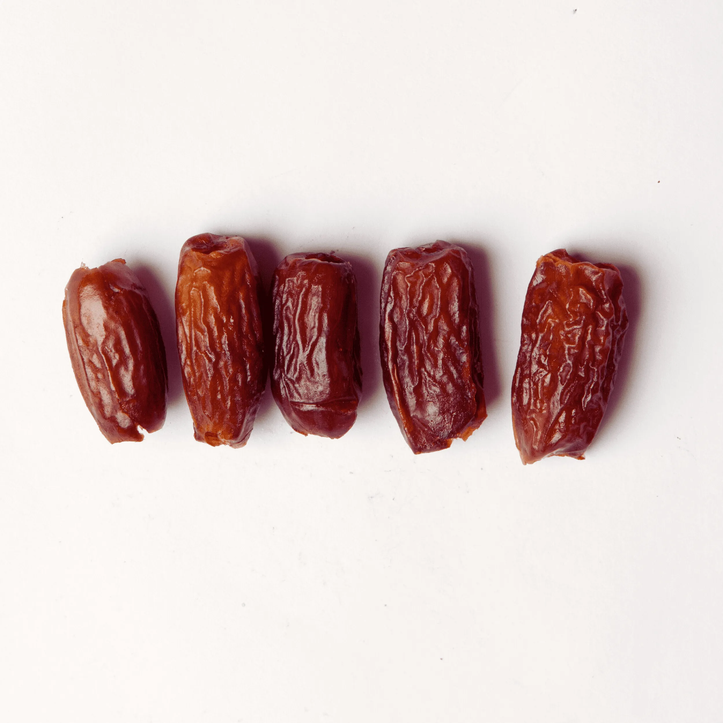 Traina® Deglet Noor Dates, pitted whole - small pile of dried fruit on white background.