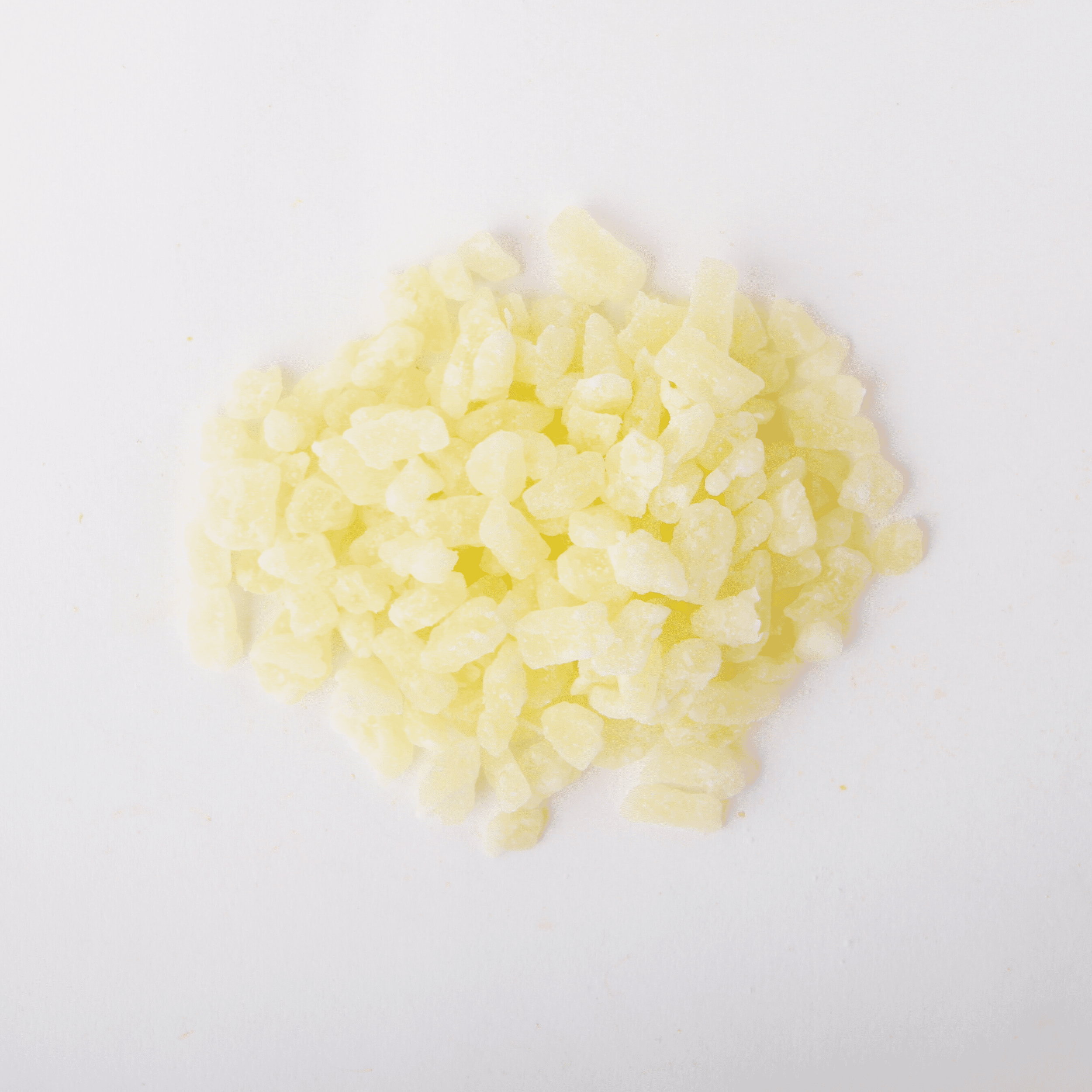 Traina® Dried Pineapple, Sweetened, with Sulfur, diced 5-7 mm - small pile of dried fruit on white background.