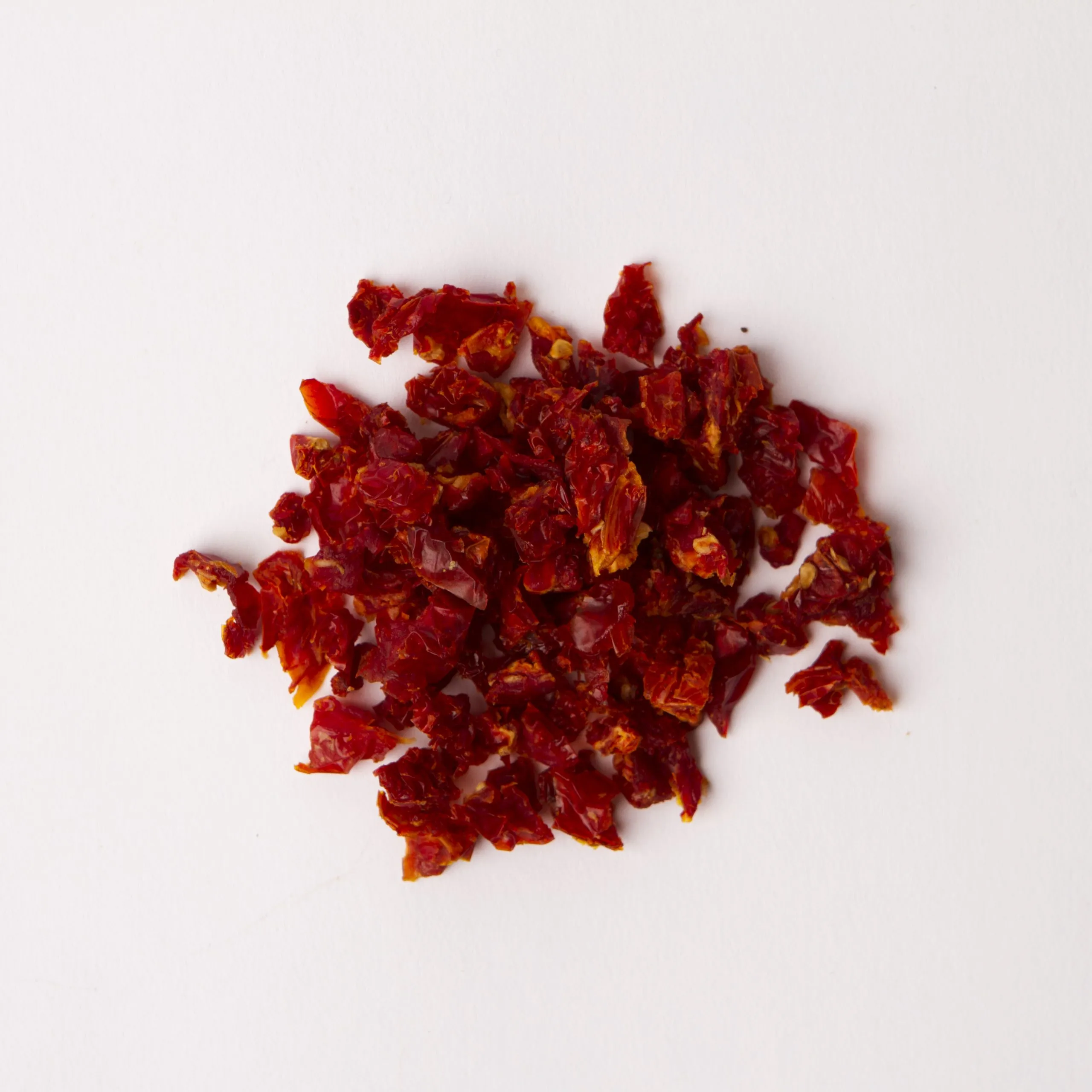 Traina® California Sun Dried Tomatoes, double-diced - small pile of sun dried tomatoes on white background.