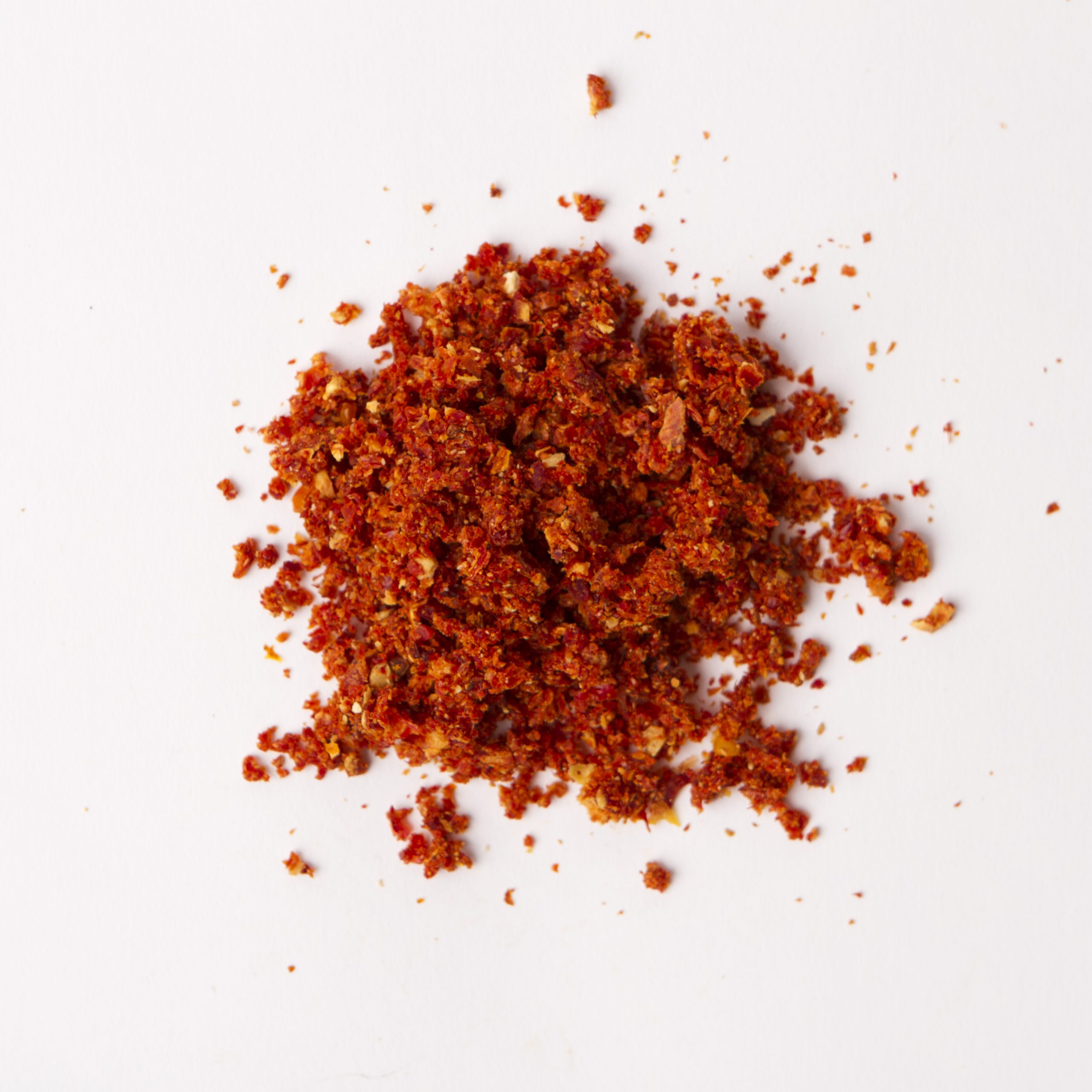 Traina® California Sun Dried Tomatoes, triple-diced - small pile of sun dried tomatoes on white background.