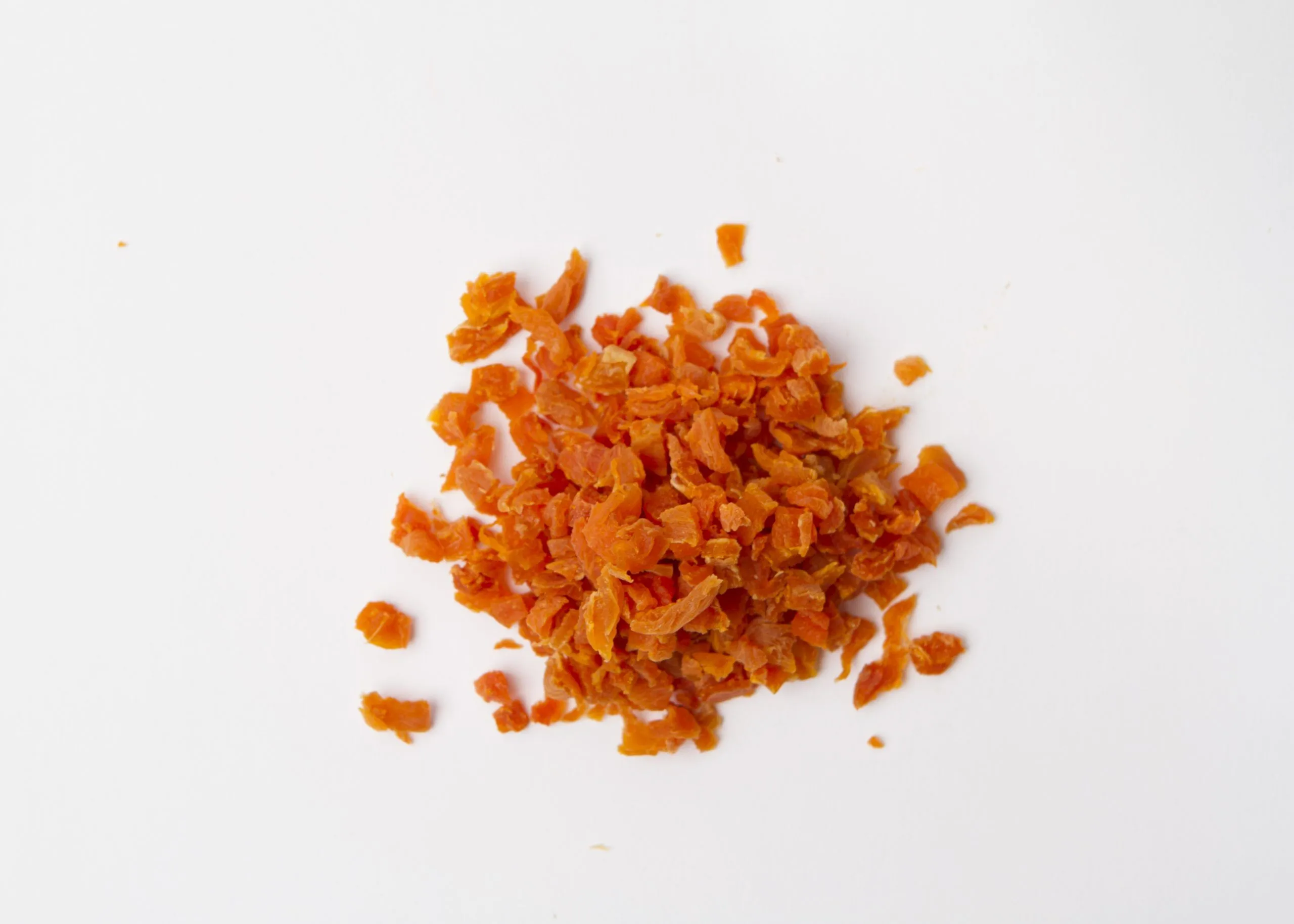 Traina® California Sun Dried Apricots, diced - small pile of sun dried fruit on white background.