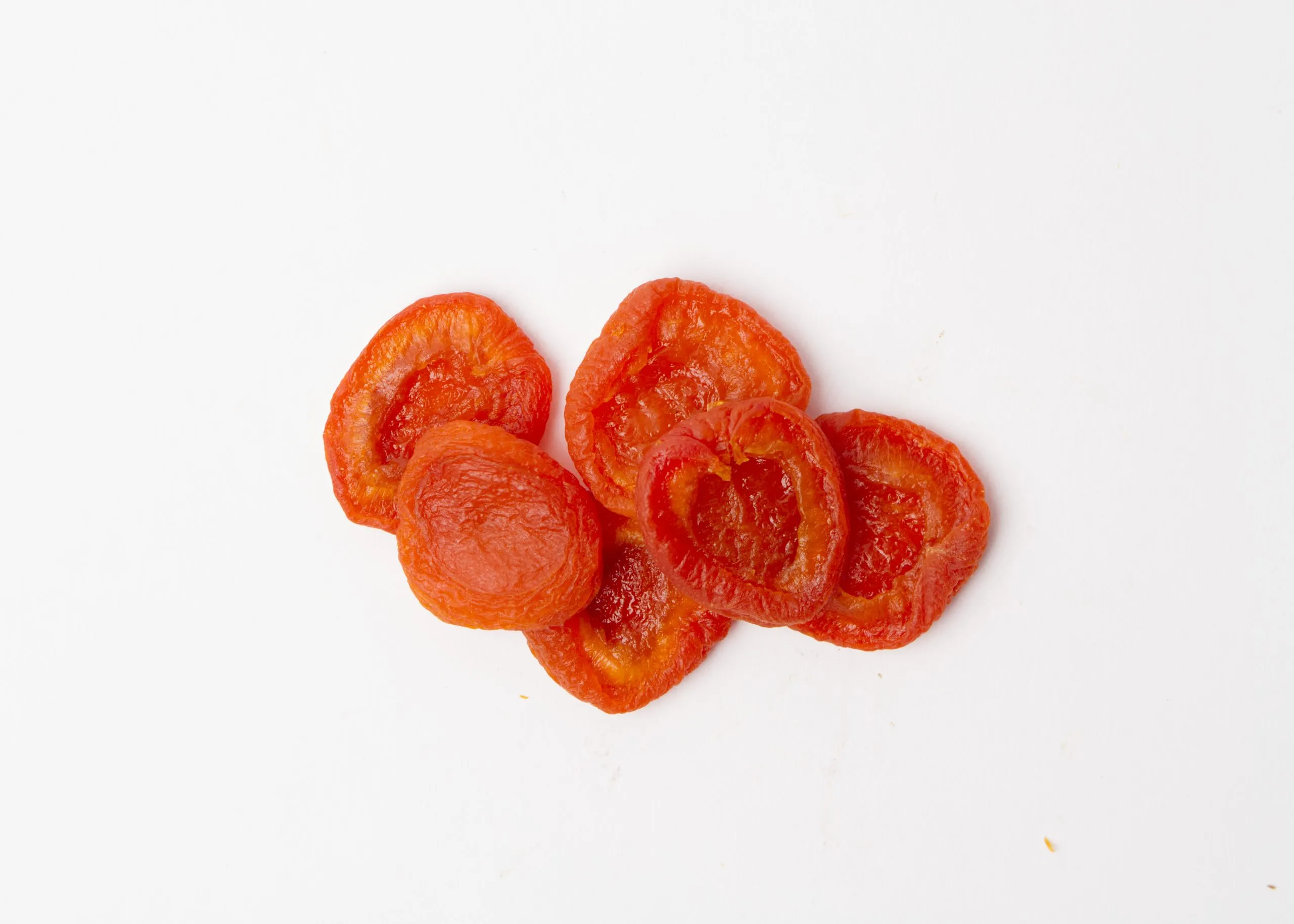 Traina® California Sun Dried Ruby Royal Apricots, Jumbo, halves - small pile of sun dried fruit on white background.