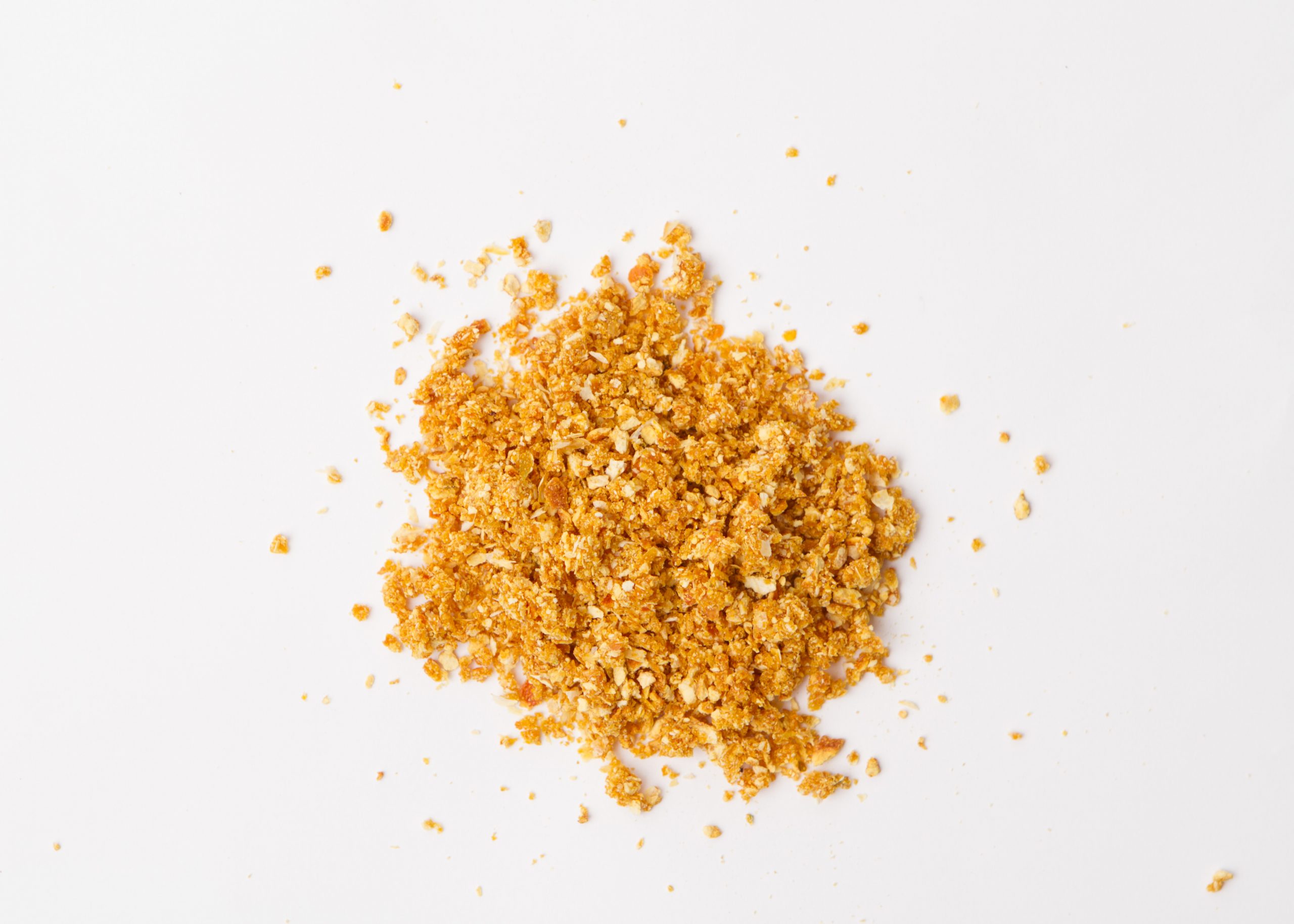 Traina® Natural Dried Tangerine, granules - small pile of dehydrated fruit on white background