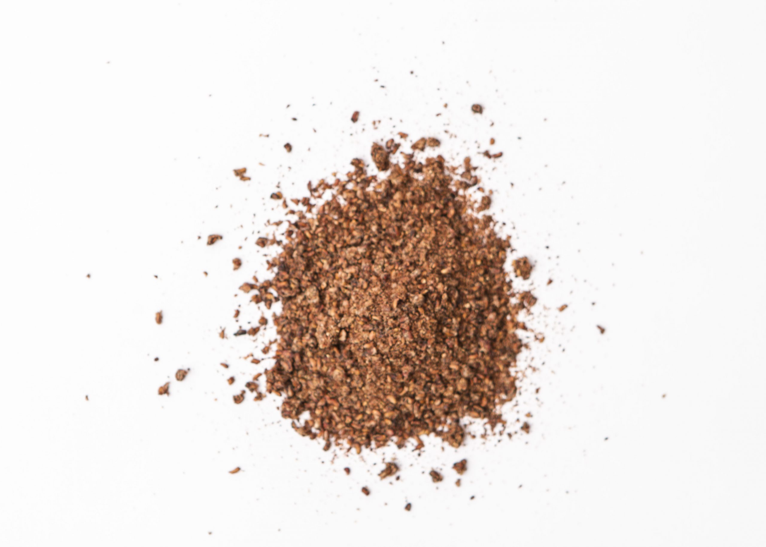 Traina® Dried Raspberry, granules - small pile of sun dried fruit on white background.