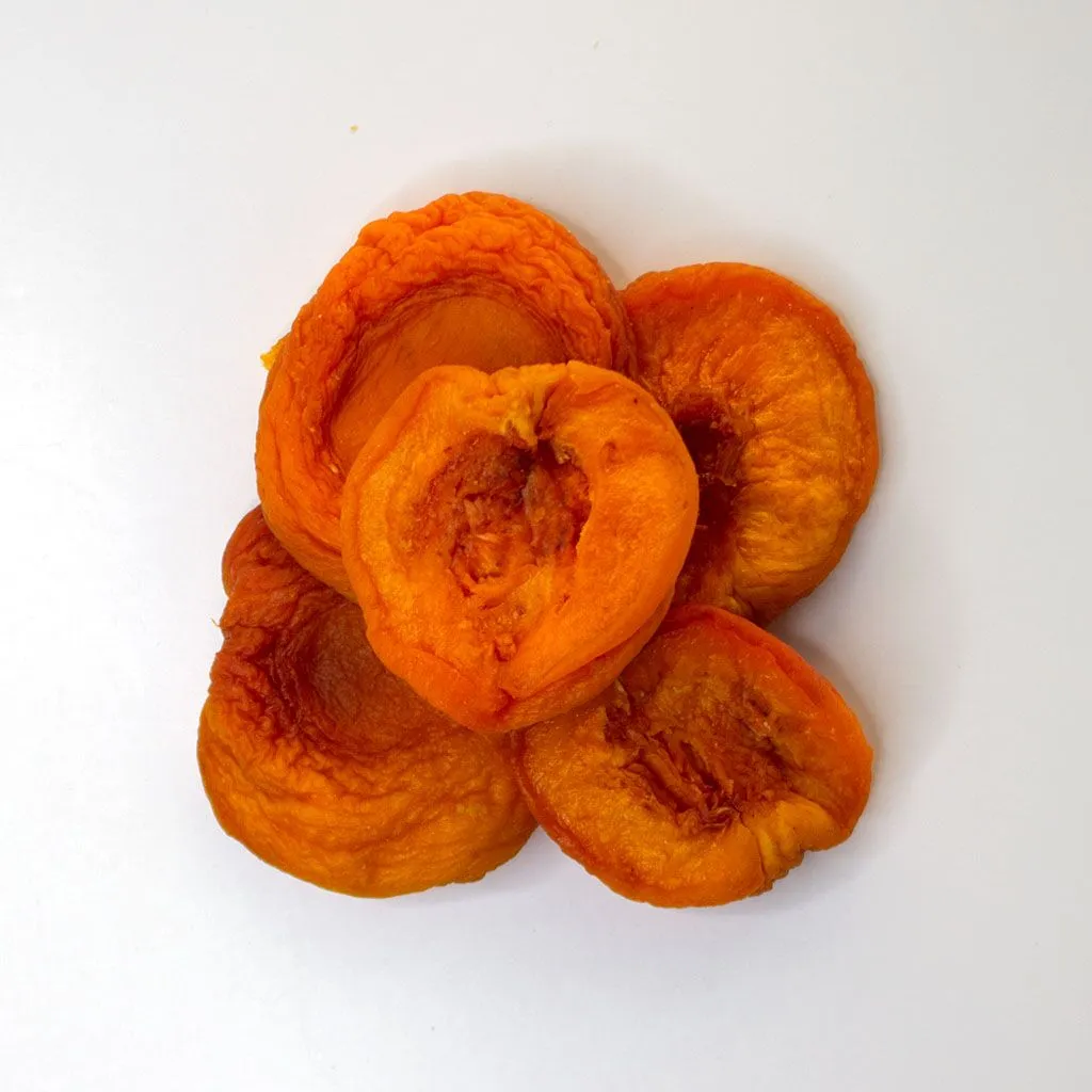 Traina® Dried Peaches, Extra Fancy halves - small pile of sun dried fruit on white background.