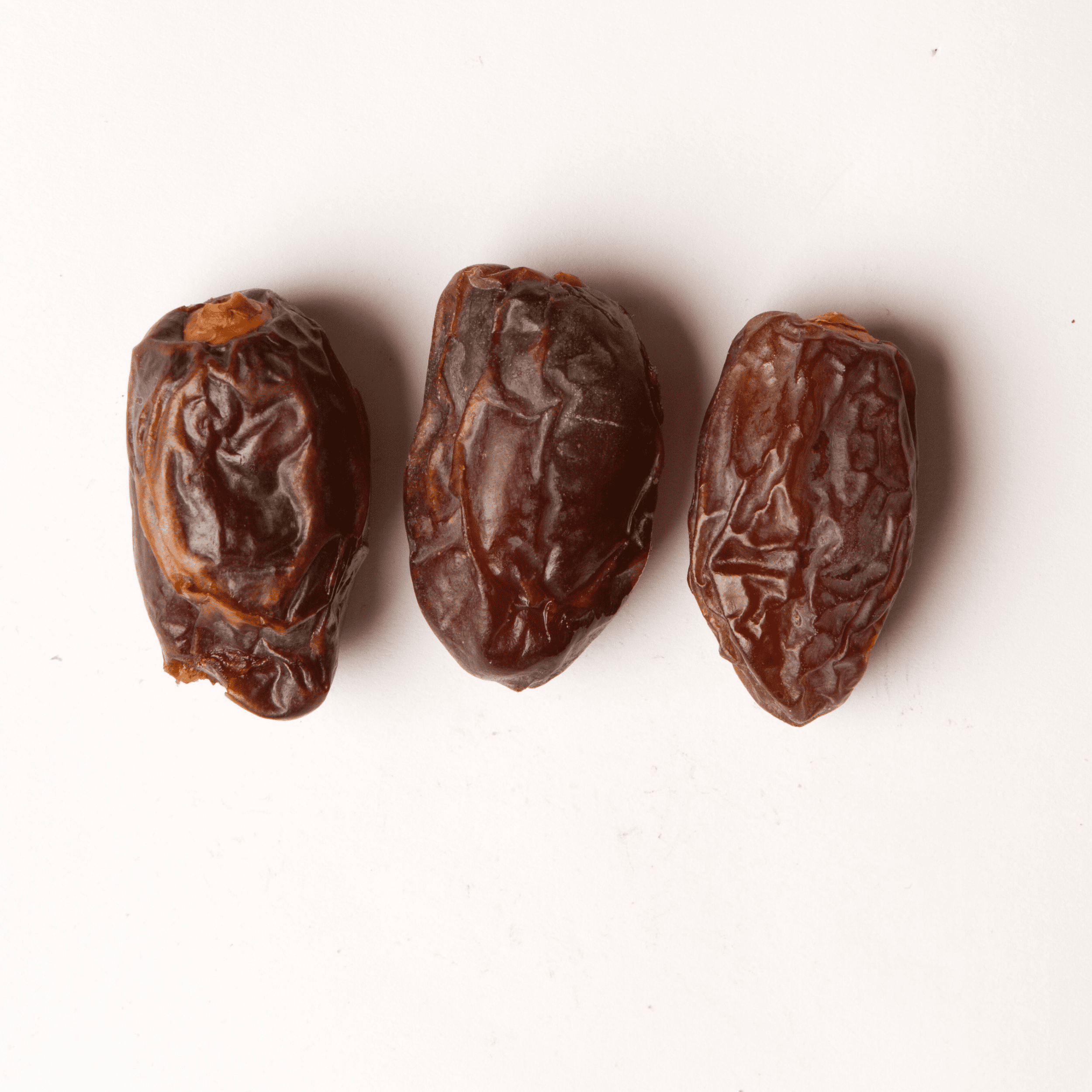 Traina® California Medjool Dates with pits - small pile of dried fruit on white background.