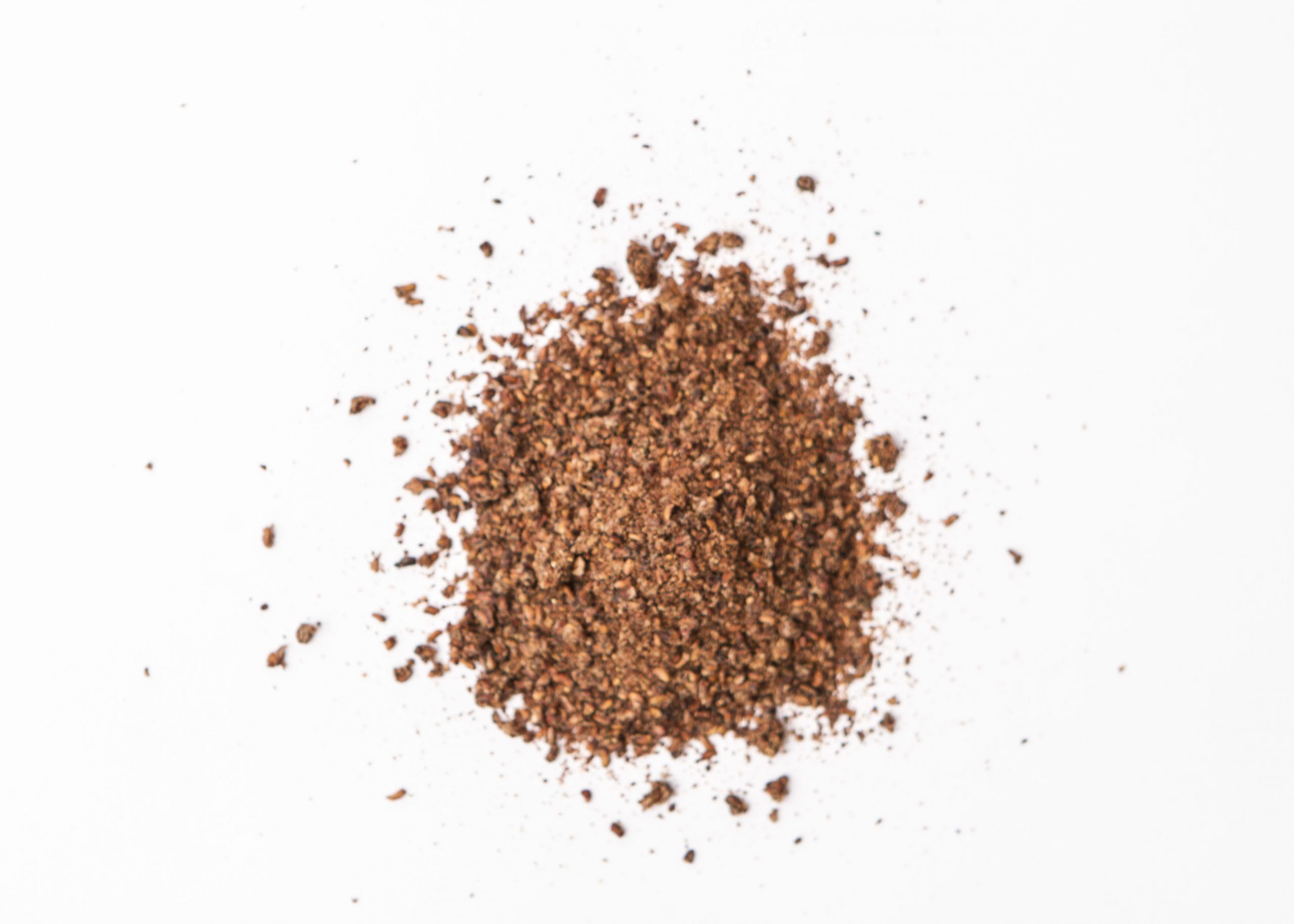 Traina® Dried Raspberry, granules - small pile of sun dried fruit on white background.