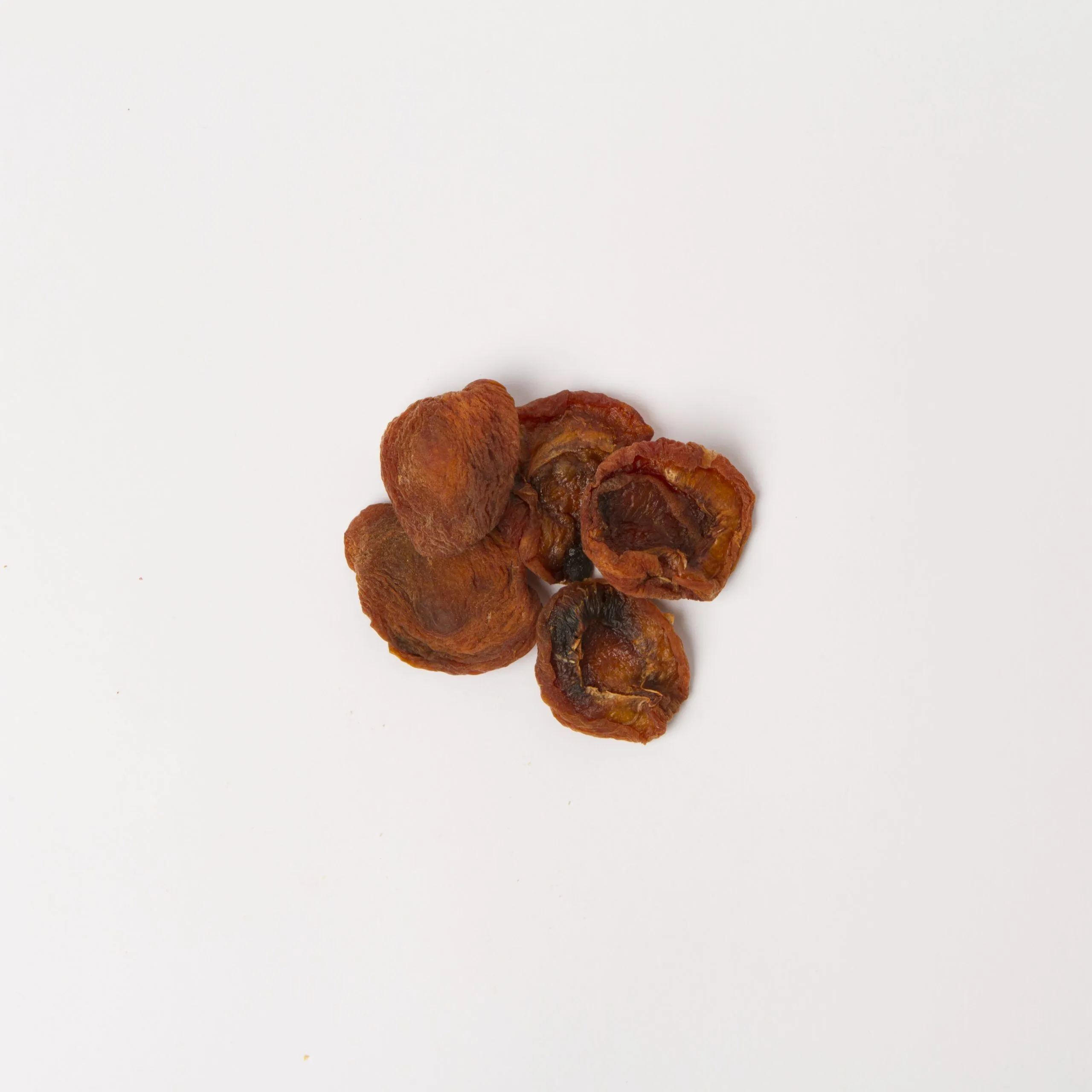 Traina® Natural California Sun Dried Apricots, halves - small pile of sun dried fruit on white background.