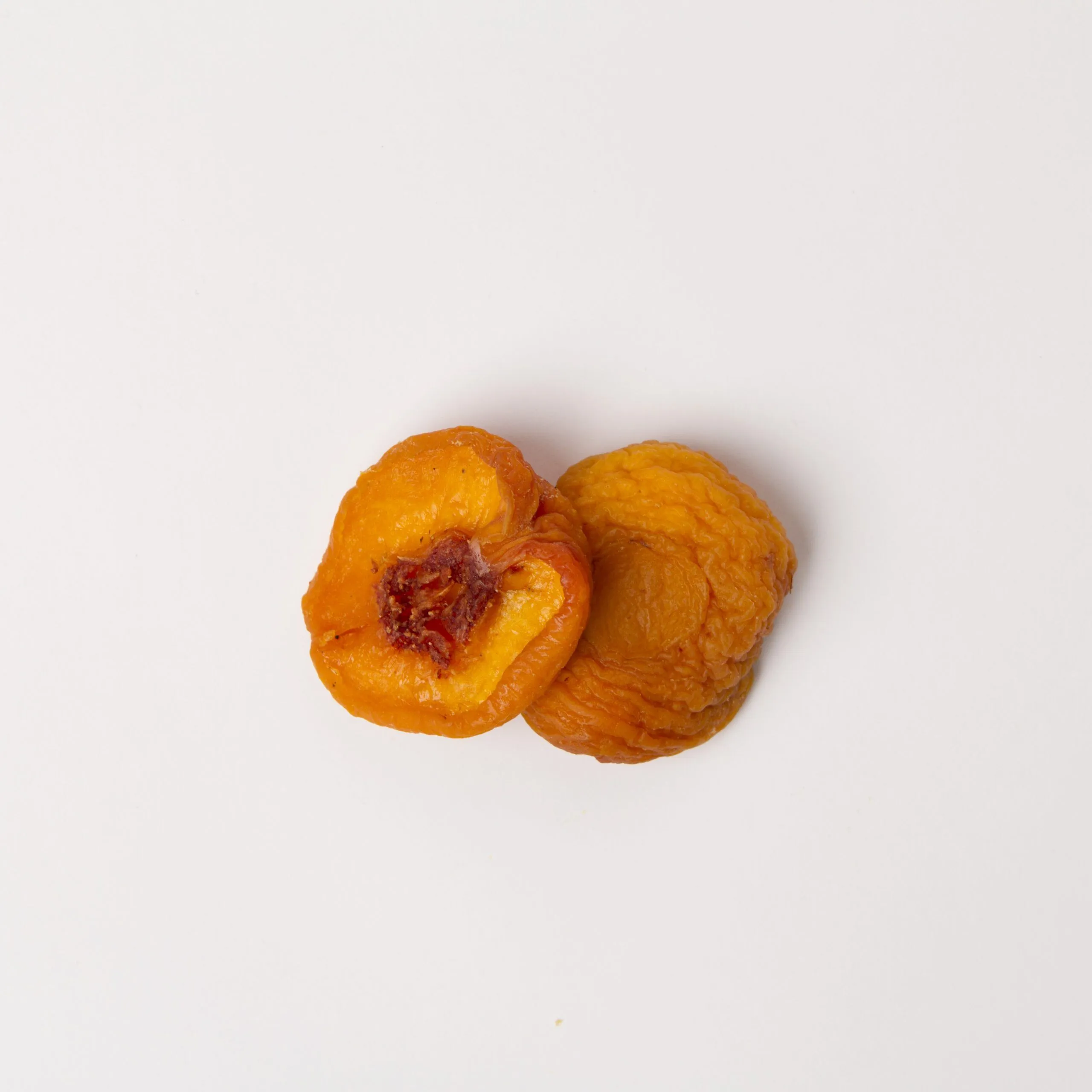 Traina® Dried Peaches, Fancy halves - small pile of sun dried fruit on white background.