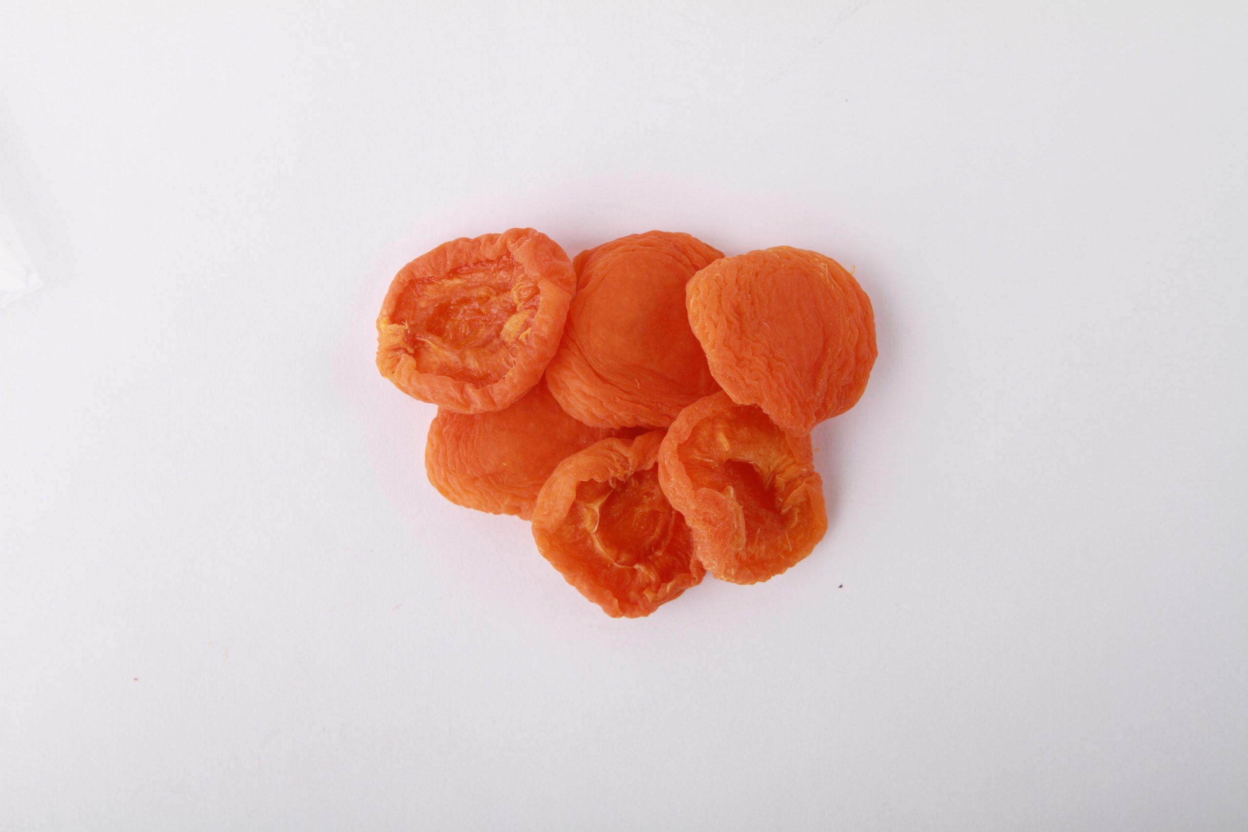 Traina® California Sun Dried Apricots, Extra Fancy, halves - small pile of sun dried fruit on white background.