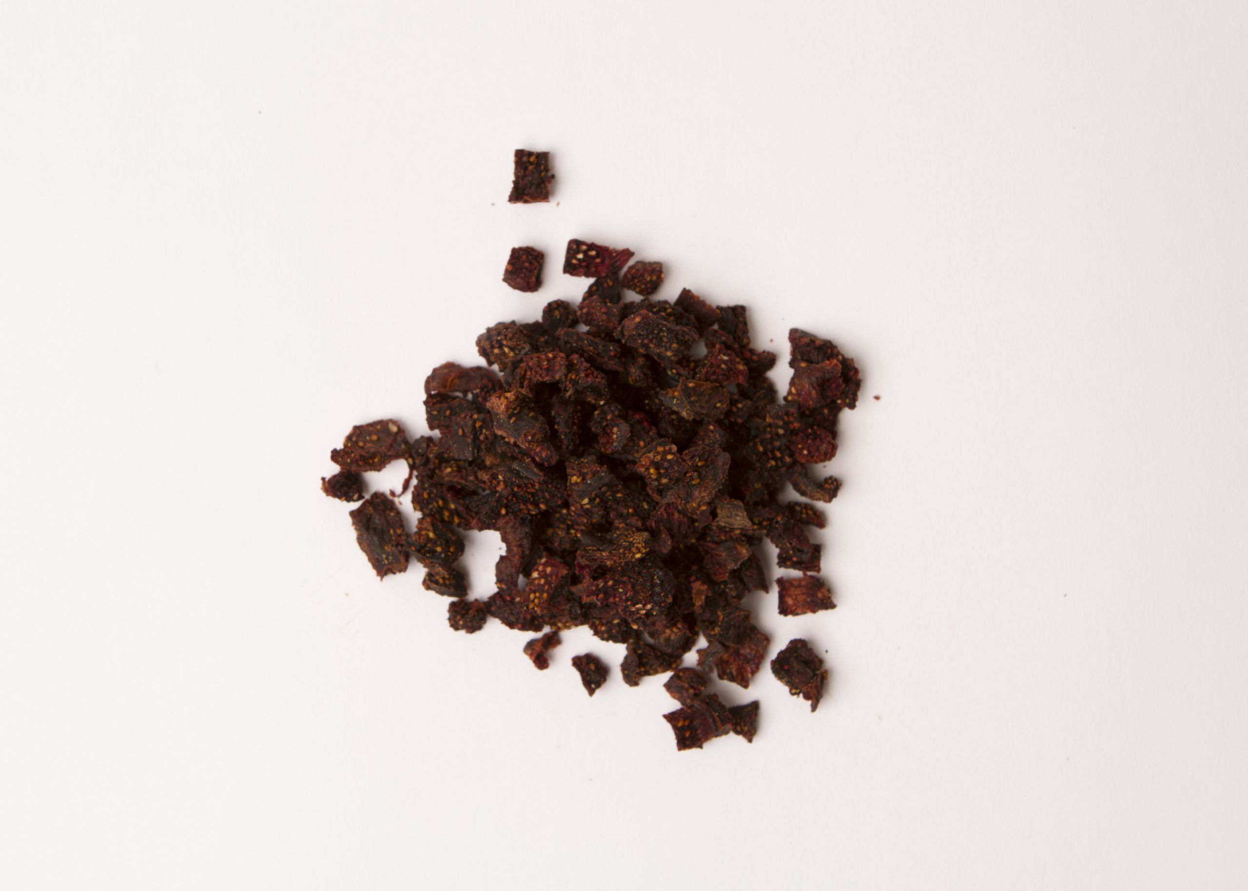 Traina® Natural Dried Strawberries, No Added Sugar, diced - small pile of sun dried fruit on white background.