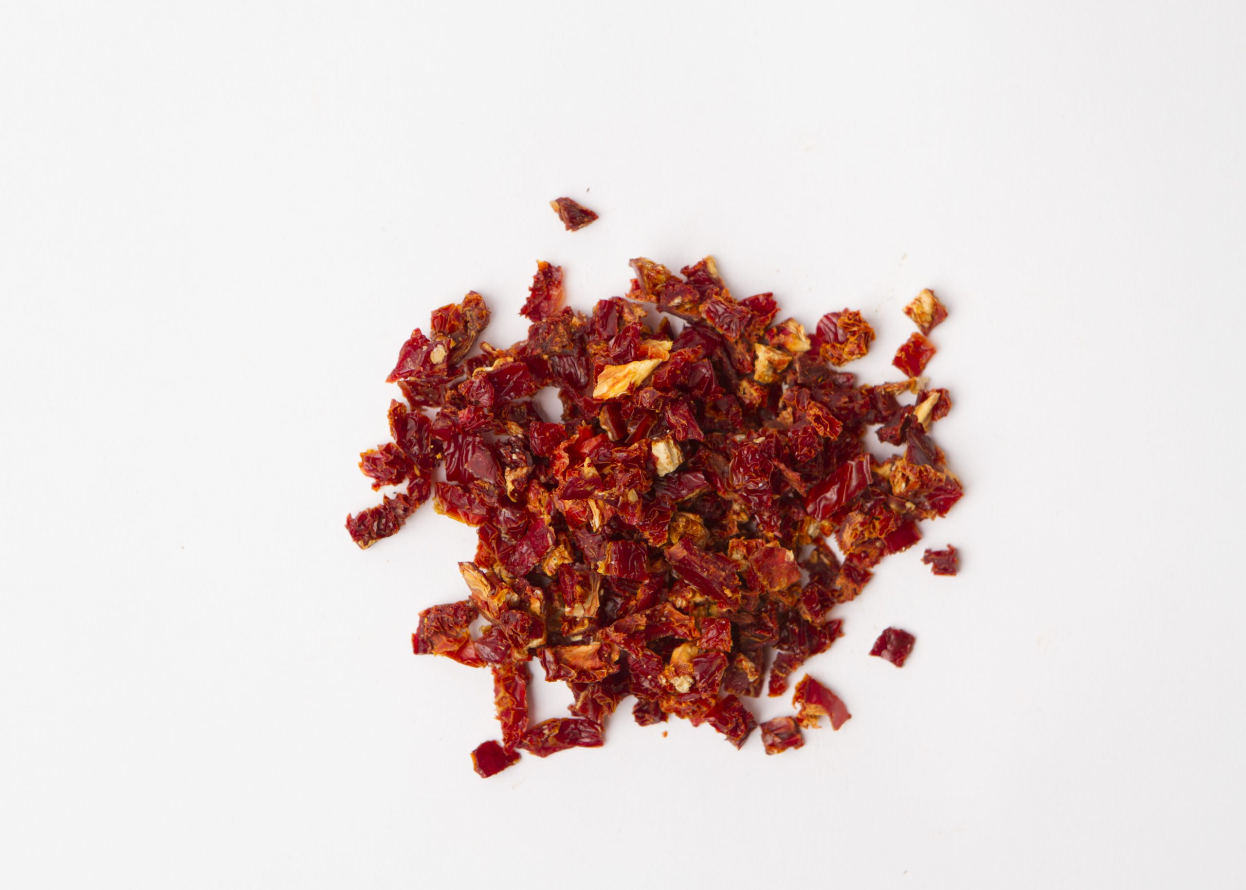 Traina® California Sun Dried Tomatoes, diced - small pile of sun dried tomatoes on white background.
