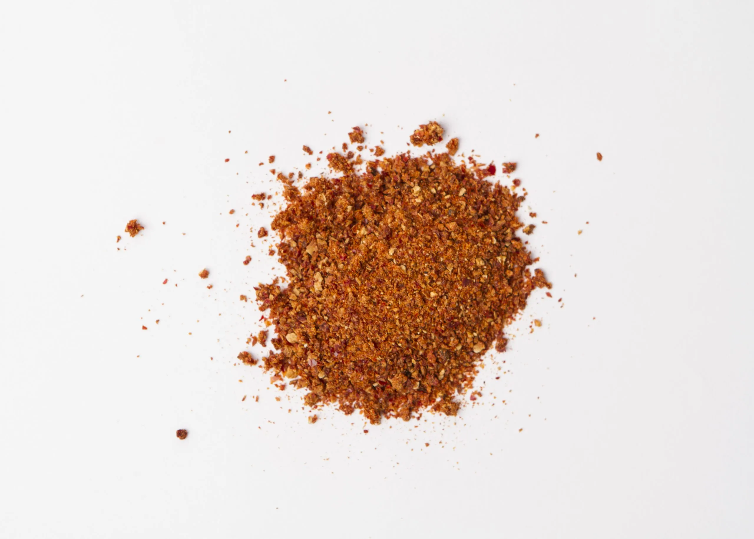 Traina® California Sun Dried Tomatoes, finely-diced - small pile of sun dried tomatoes on white background.
