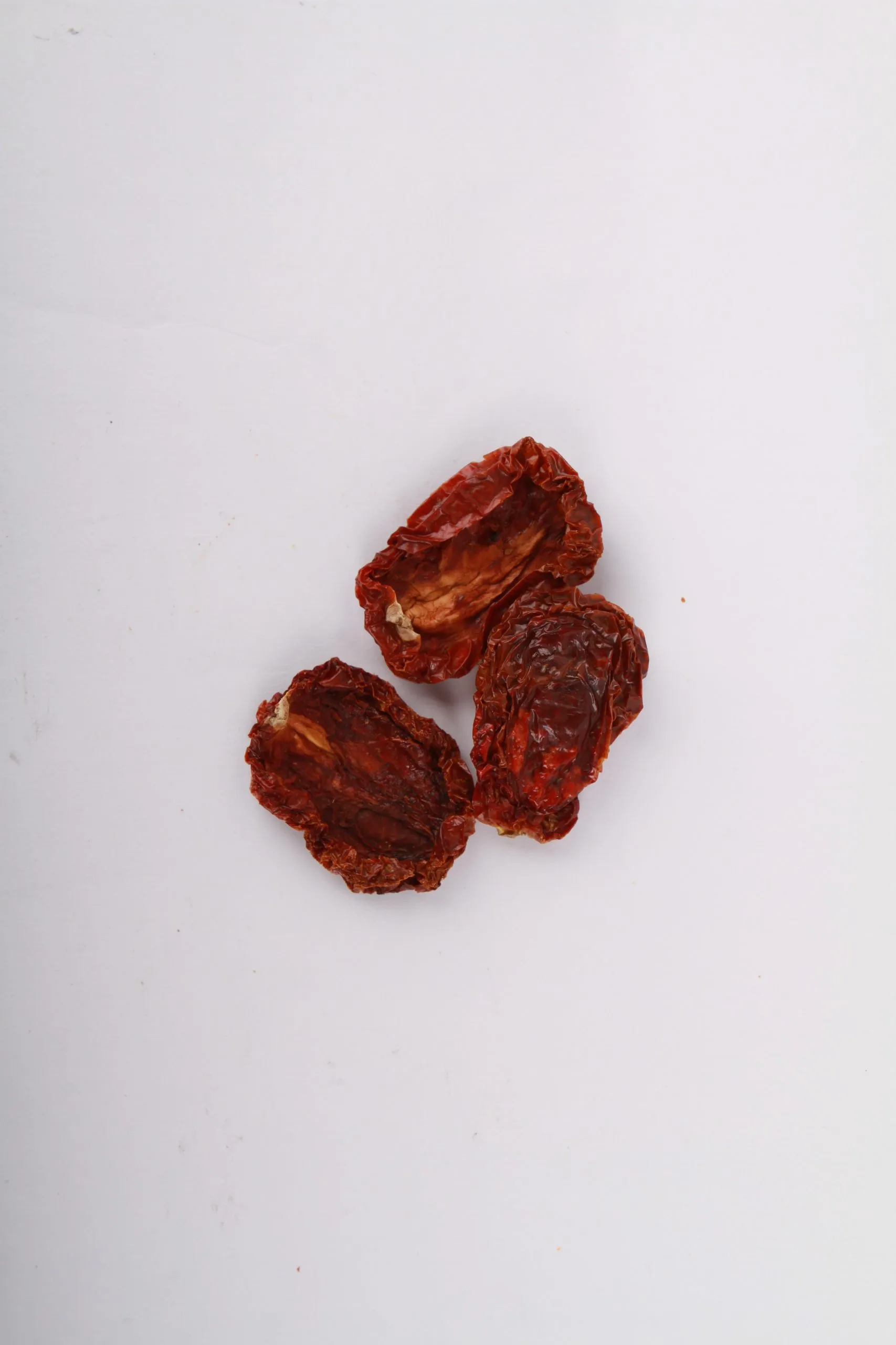 Traina® Natural California Sun Dried Tomatoes, with salt, halves - small pile of sun dried tomatoes on white background.