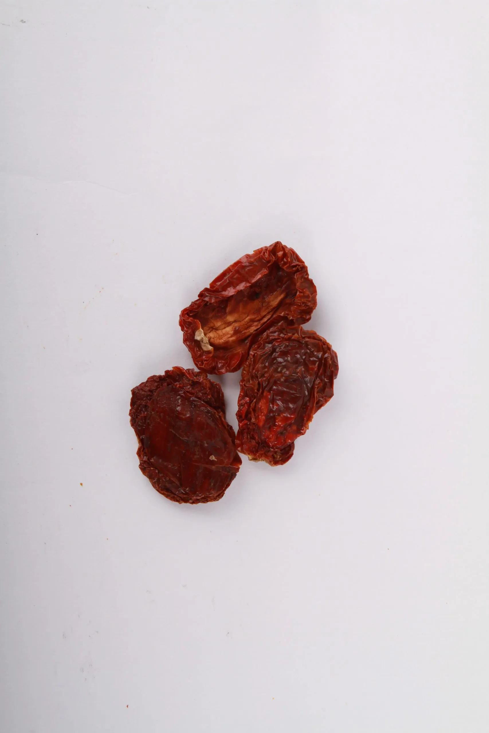 Natural California Sun Dried Tomatoes, No Salt - Halves. Small pile of sun dried tomatoes on white background.