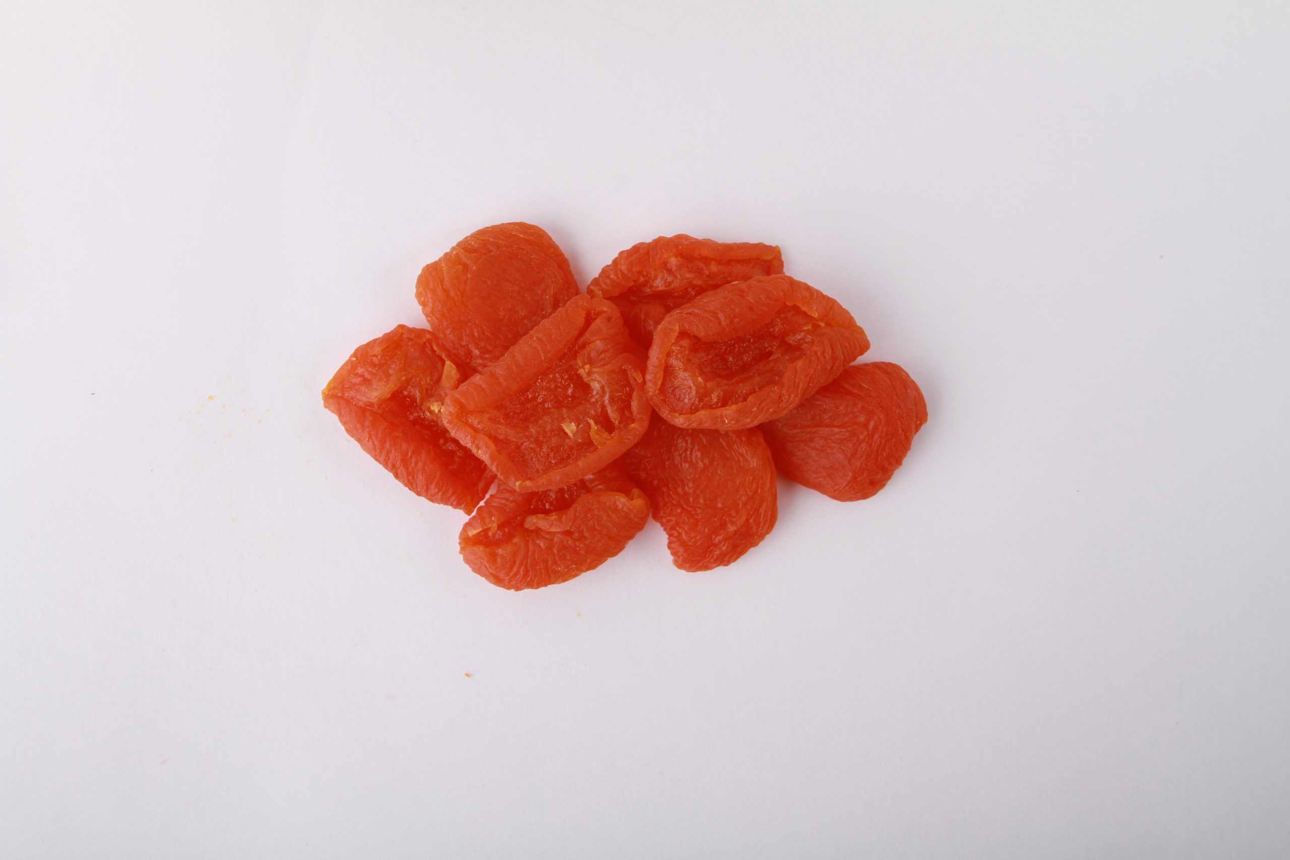 Traina® California Sun Dried Ruby Royal Apricots, Extra Choice, halves - small pile of sun dried fruit on white background.