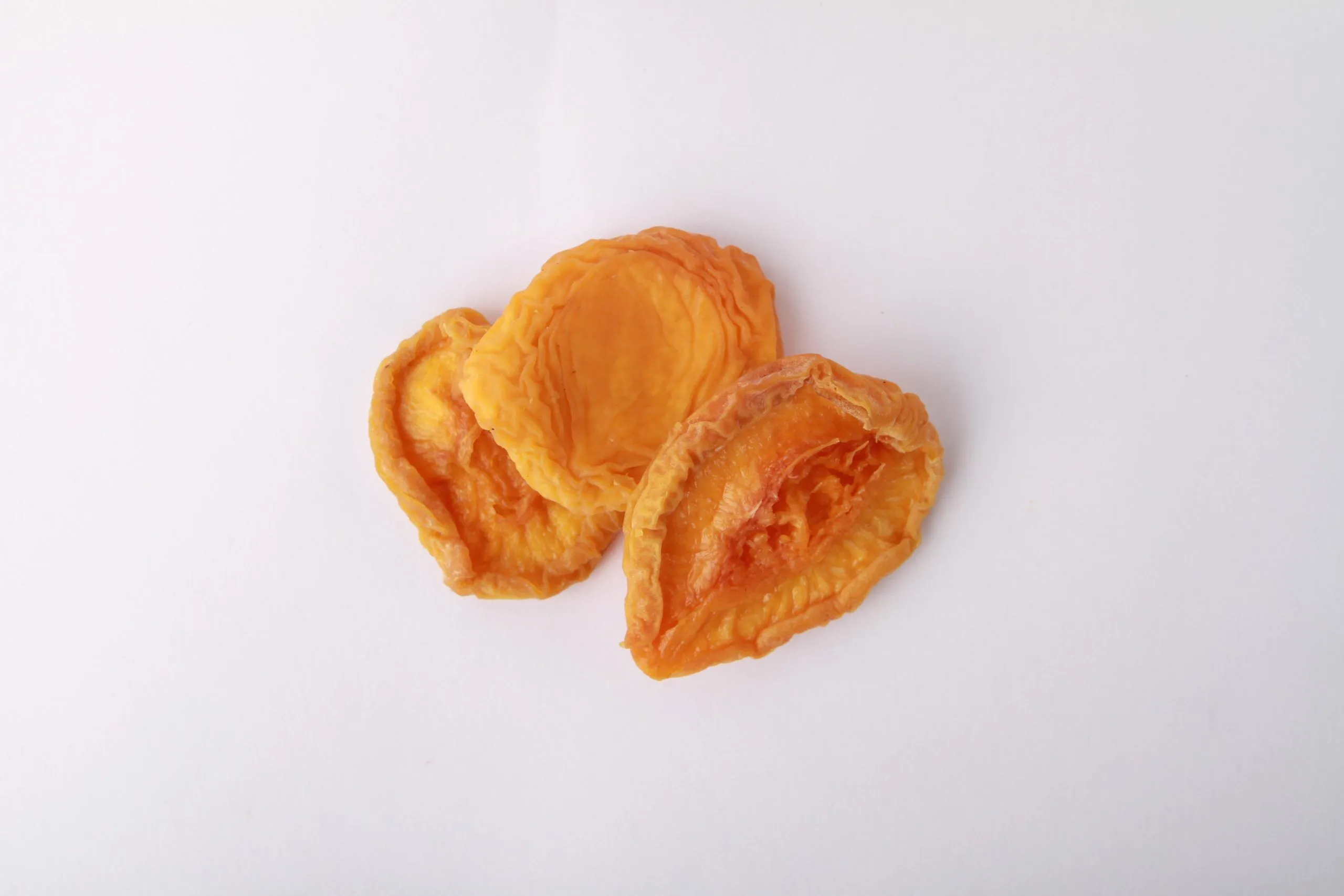 Traina® Dried Peaches, Extra Choice halves- small pile of sun dried fruit on white background.