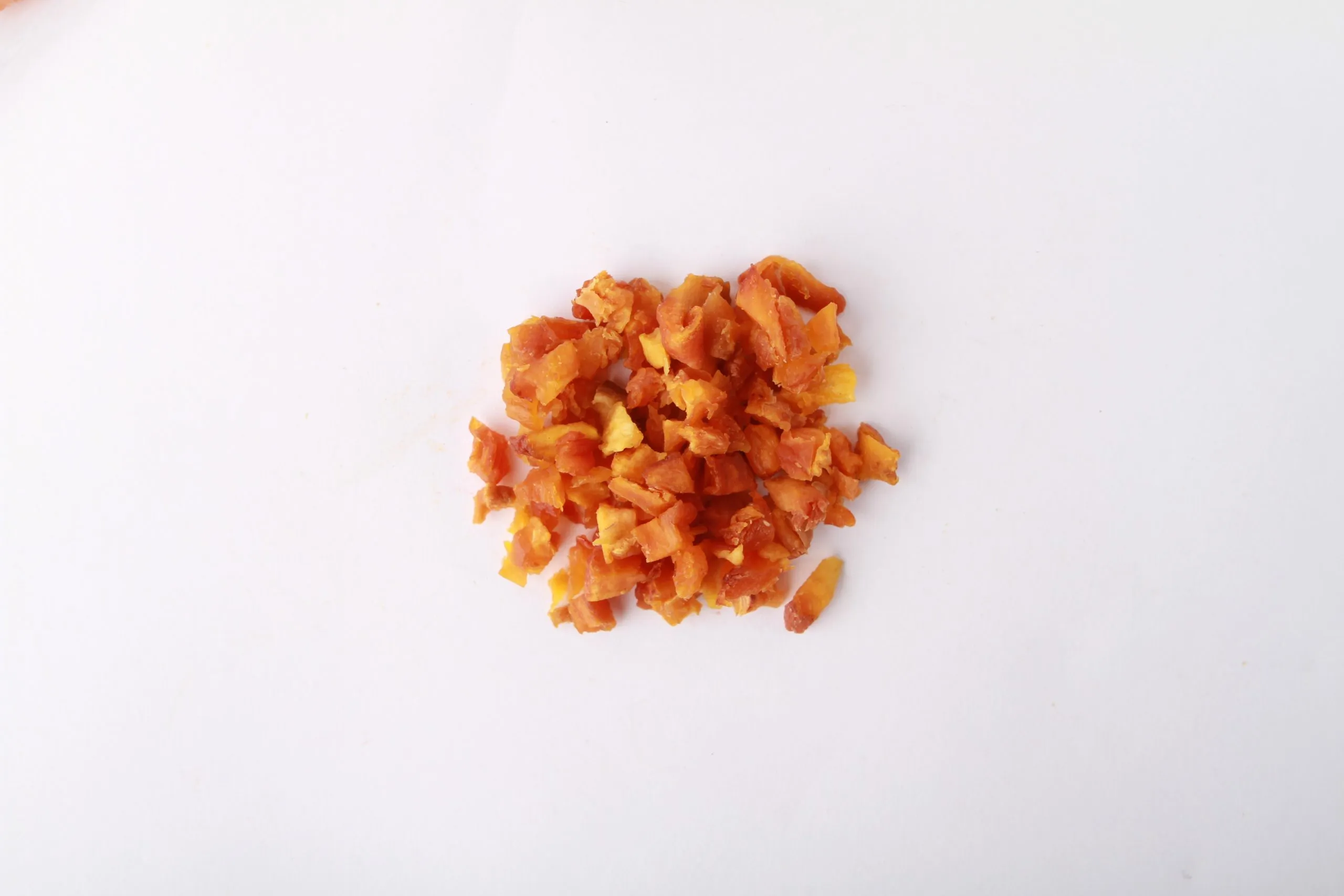 Traina® Dried Peaches double-diced - small pile of sun dried fruit on white background.