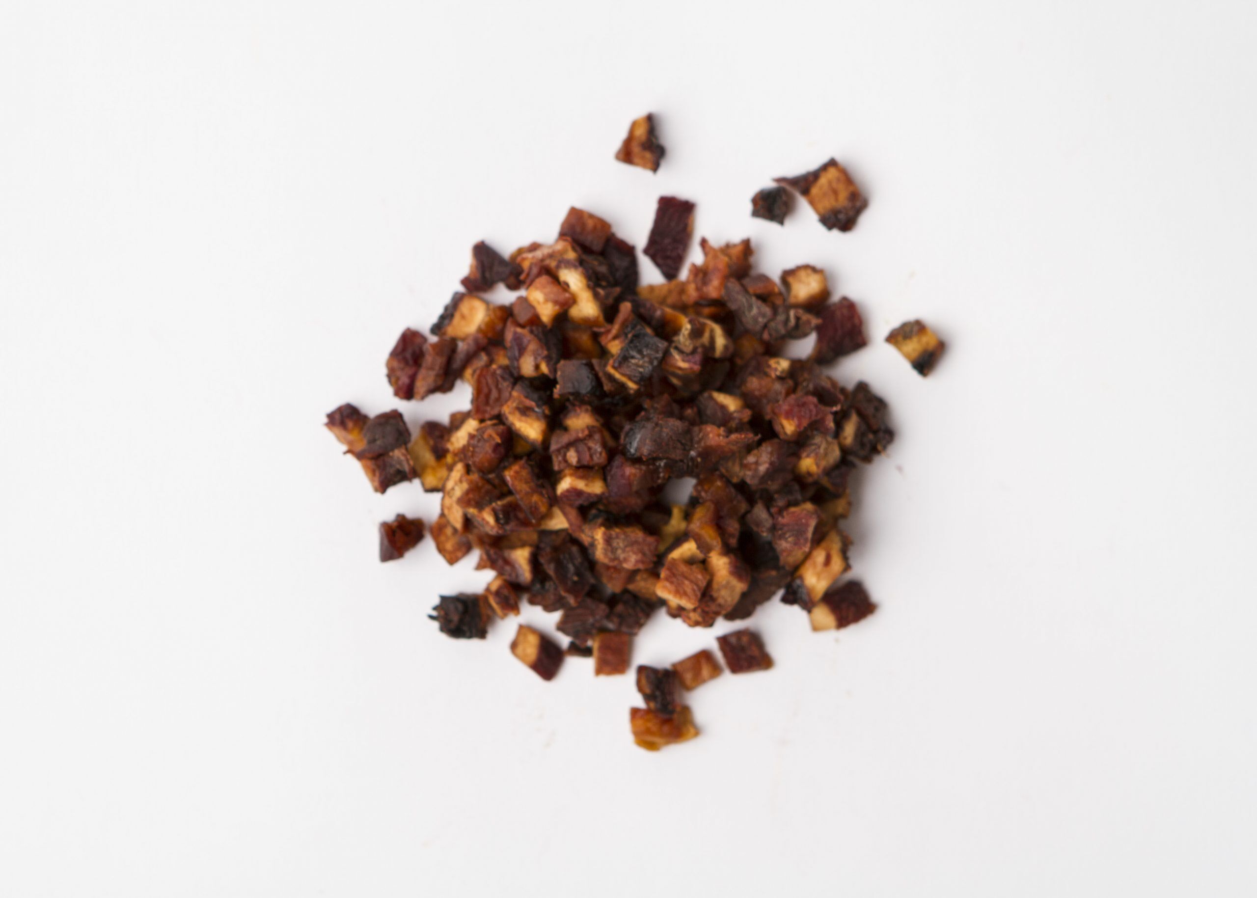 Traina® Natural California Sun Dried Peaches, diced - small pile of sun dried fruit on white background.