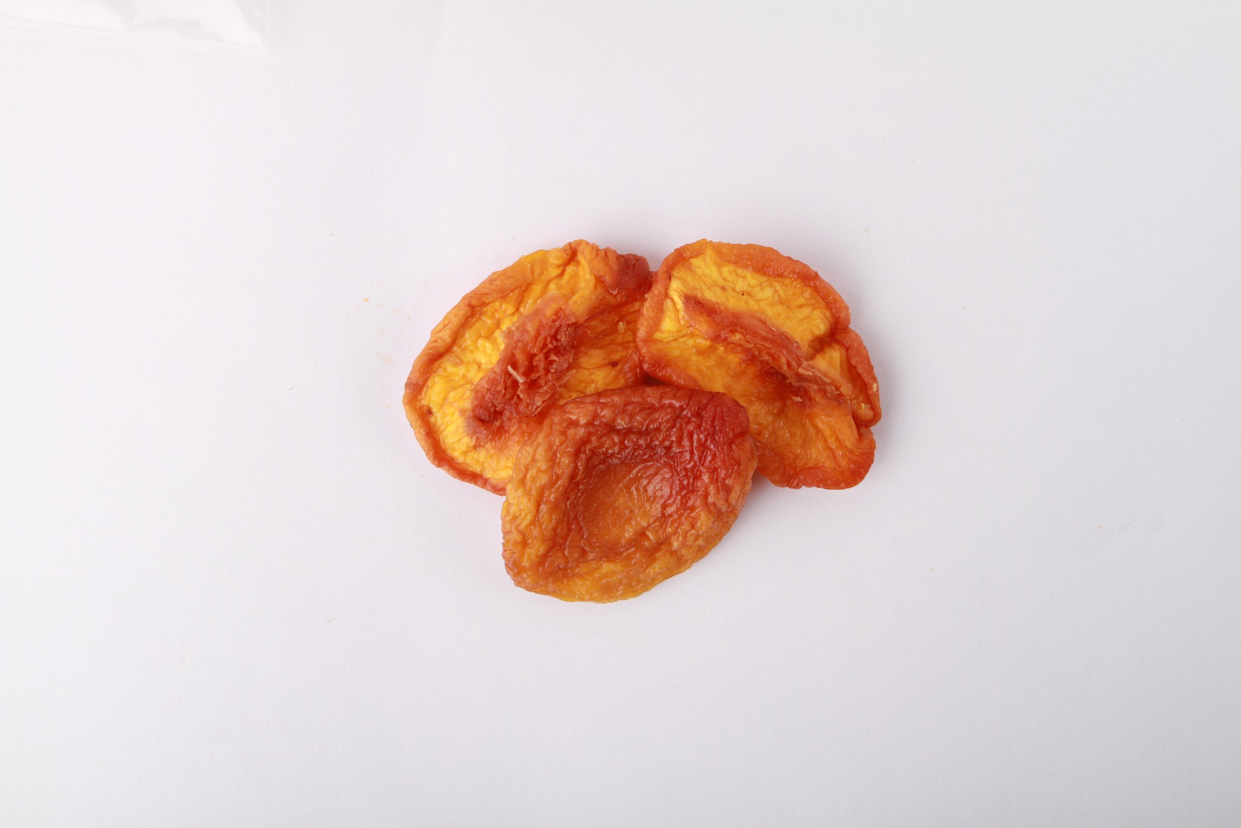 Traina® California Sun Dried Nectarines, Extra Choice, halves - small pile of sun dried fruit on white background.