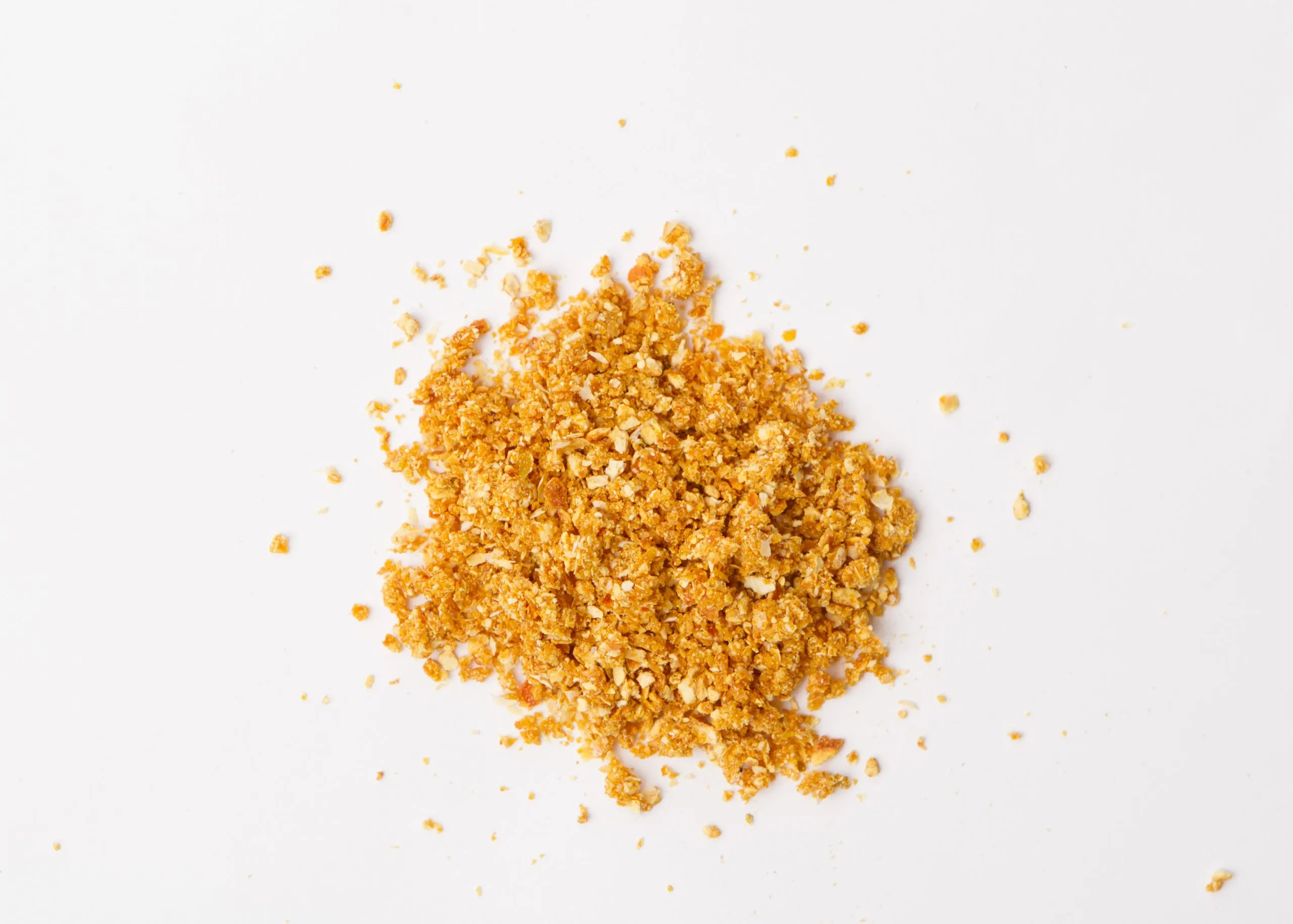 Traina® Natural Dried Tangerine, granules - small pile of dehydrated fruit on white background