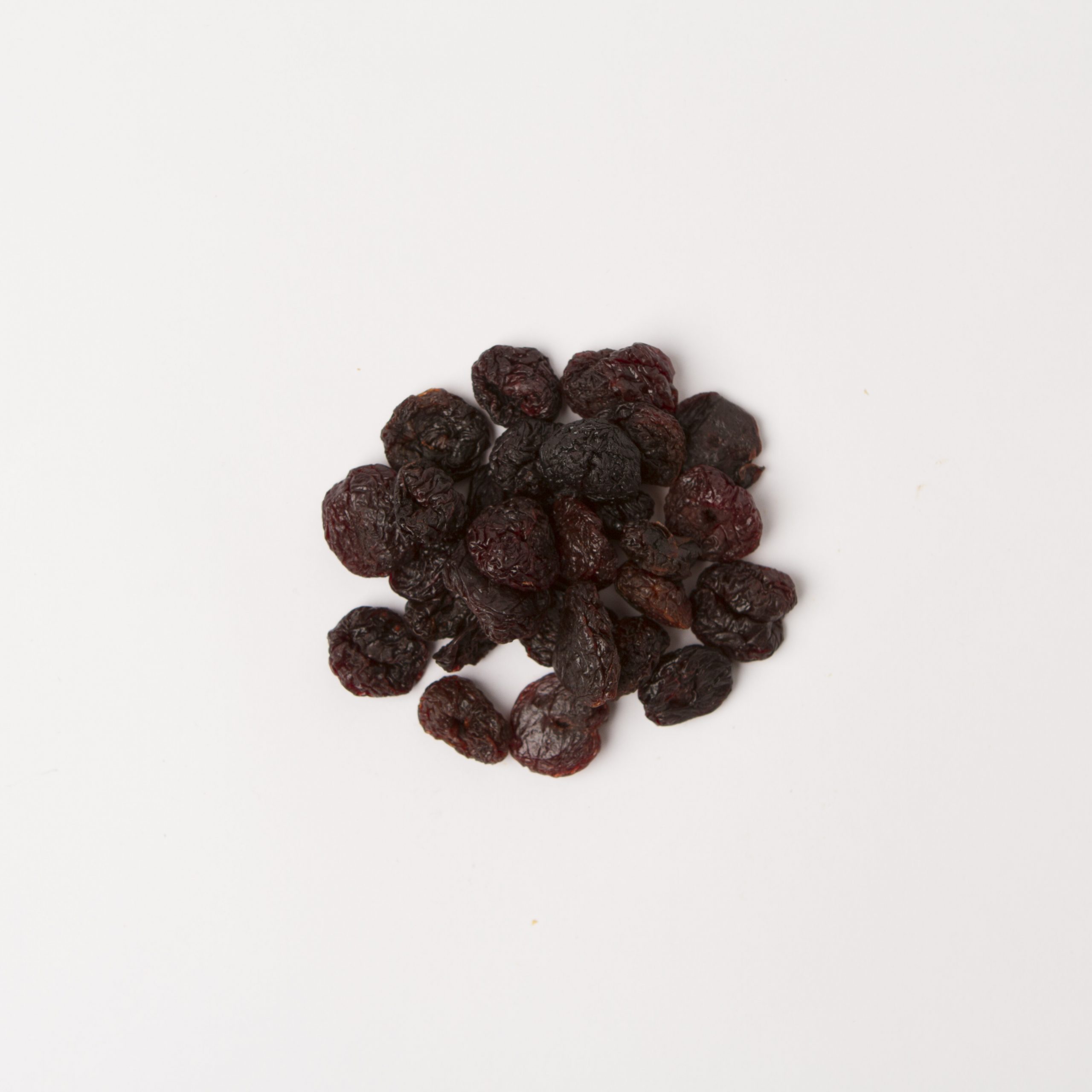 Traina® California Sun Dried Bing Cherries, pitted, whole - small pile of sun dried fruit on white background.