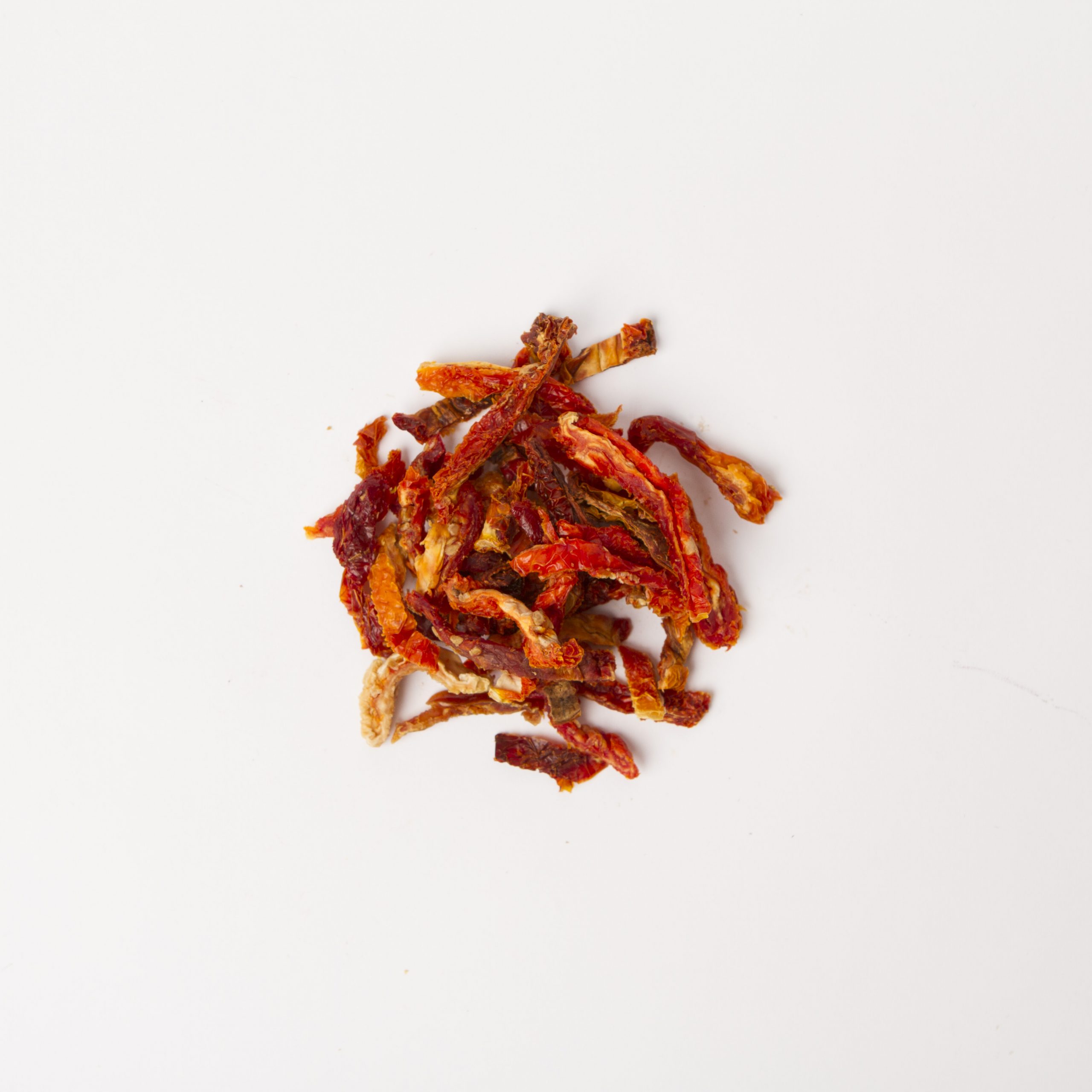 Small pile of Julienne Cut Mediterranean Sun Dried Tomatoes on white background.