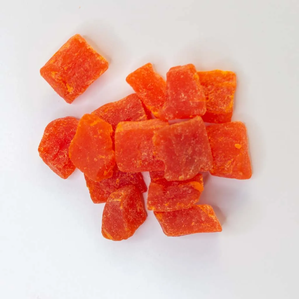 Traina® Dried Papaya, Sweetened,-chunks. Small pile of dried fruit on white background.