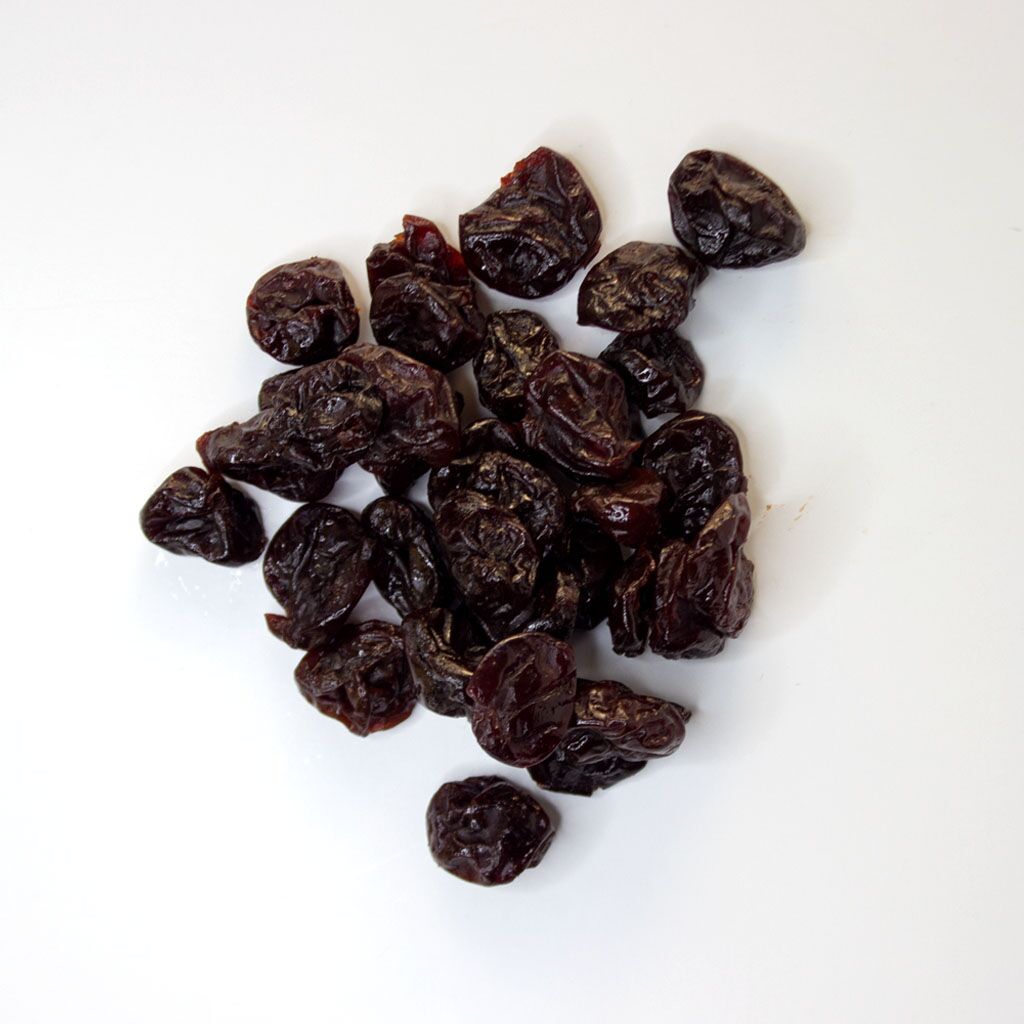 Traina® Dried Tart Cherries, sweetened, Pitted, whole - small pile of dried fruit on white background.