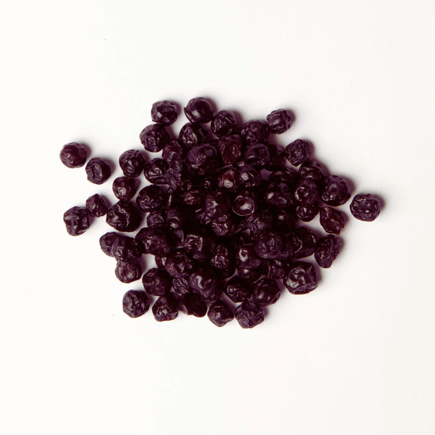 Traina® Dried Blueberries, Sweetened, whole - small pile of dried fruit on white background.