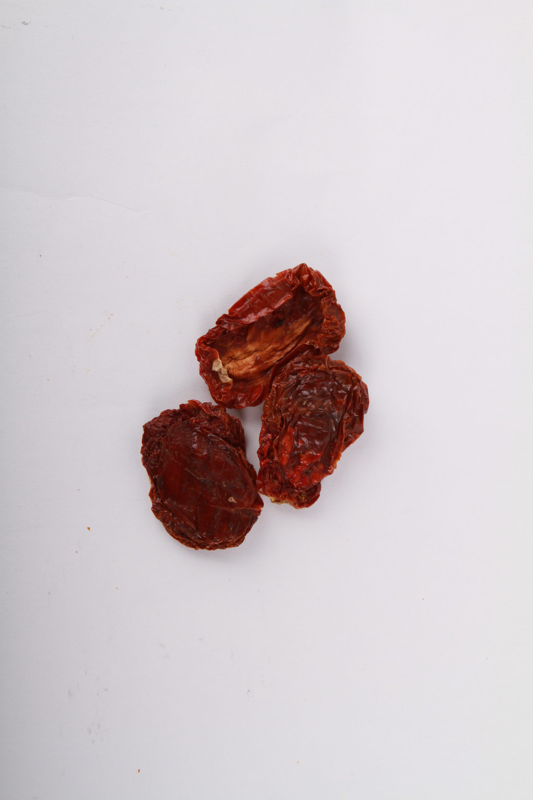 Natural California Sun Dried Tomatoes, No Salt - Halves. Small pile of sun dried tomatoes on white background.