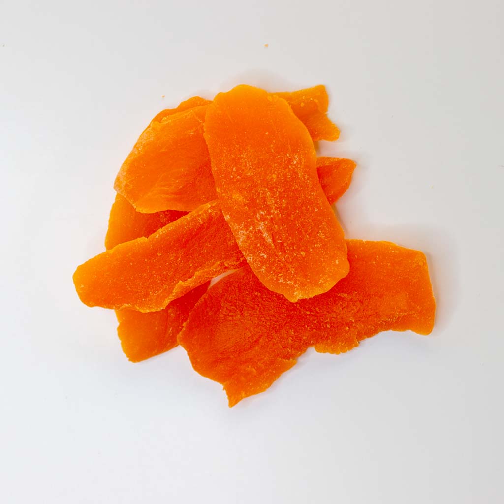 Traina® Dried Mango, Sweetened - Slices. Small pile of dried fruit on white background.