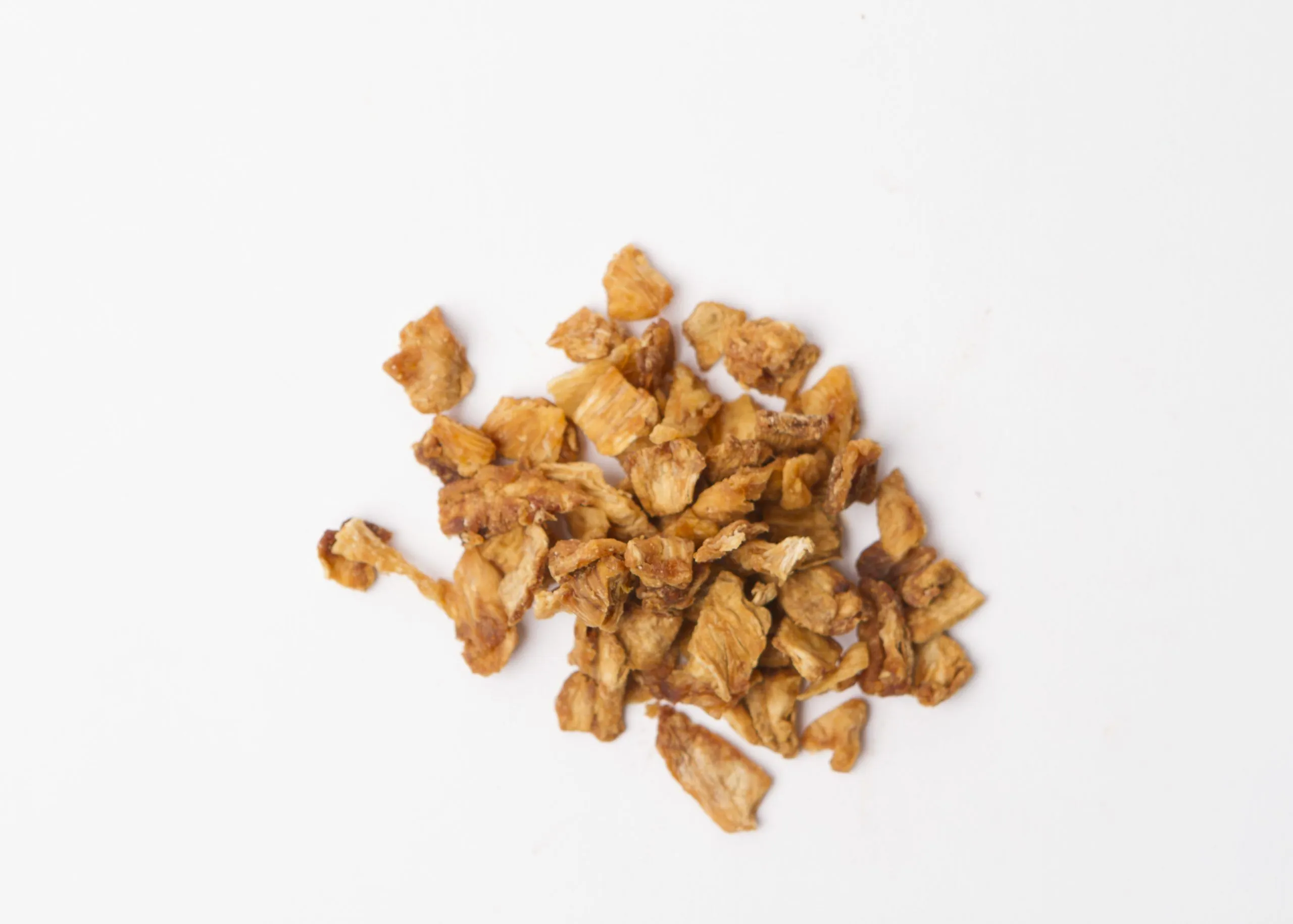 Traina® Organic Dried Pineapple, chunks 5-8 mm - small pile of dried fruit on white background.