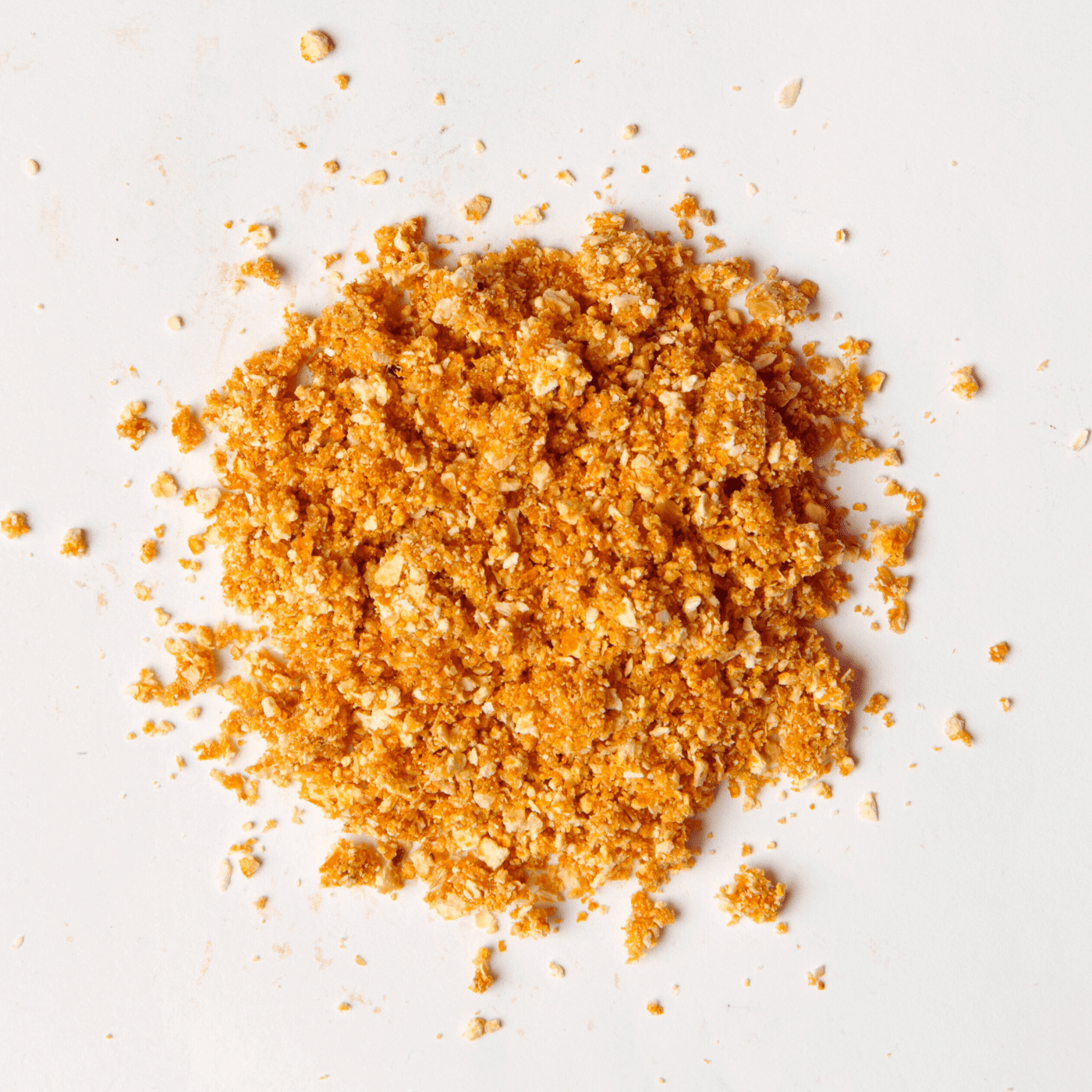 Traina® Organic Dried Orange, granules - small pile of dehydrated fruit on white background