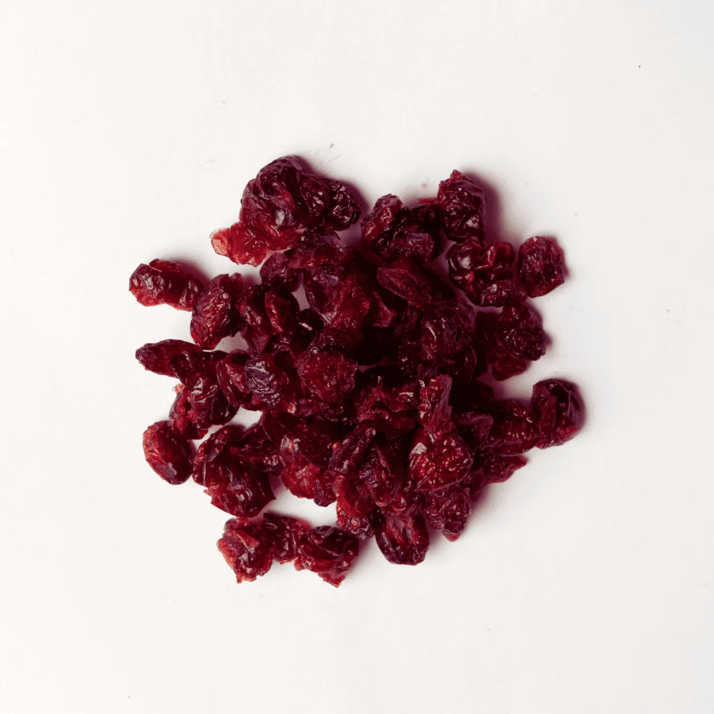 Traina® Dried Cranberries, Sweetened, whole - small pile of dried fruit on white background.