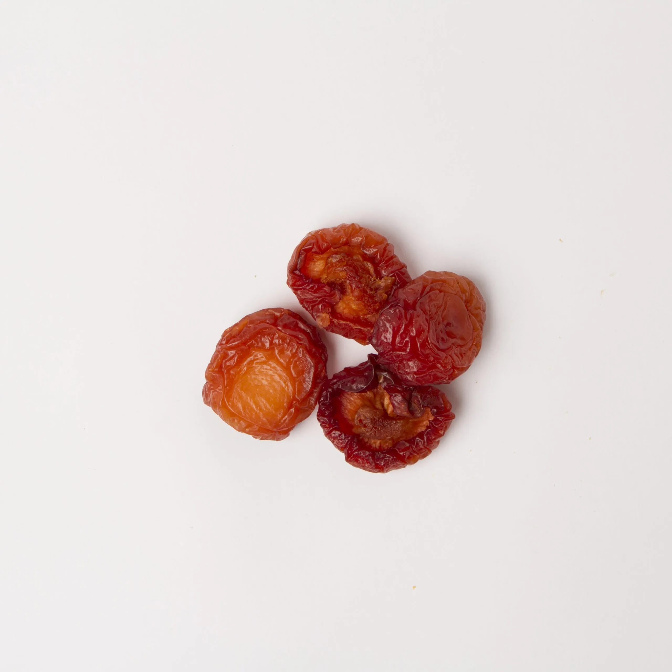 Traina® California Sun Dried Angelino Plums, Fancy, halves - small pile of sun dried fruit on white background.
