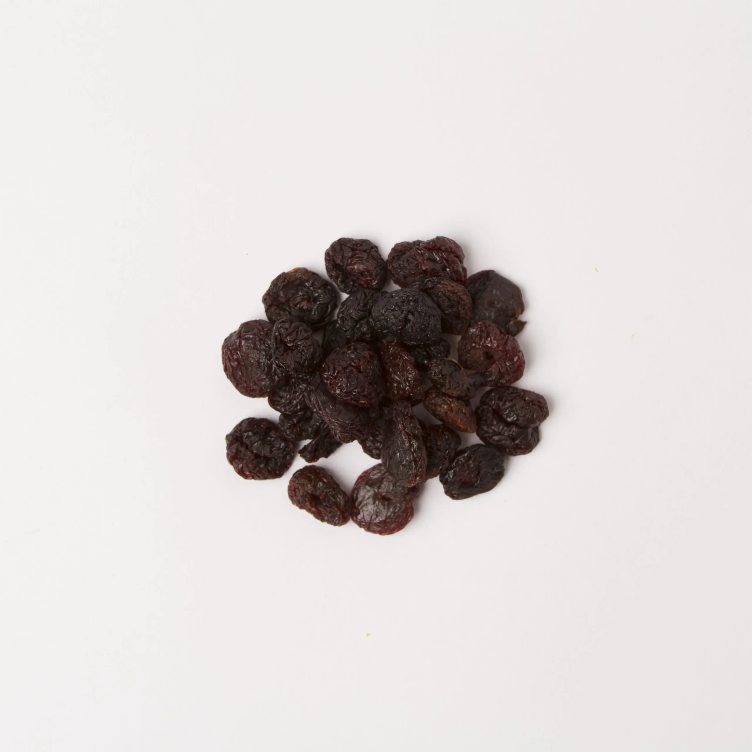 Traina® California Sun Dried Bing Cherries, pitted, whole - small pile of sun dried fruit on white background.
