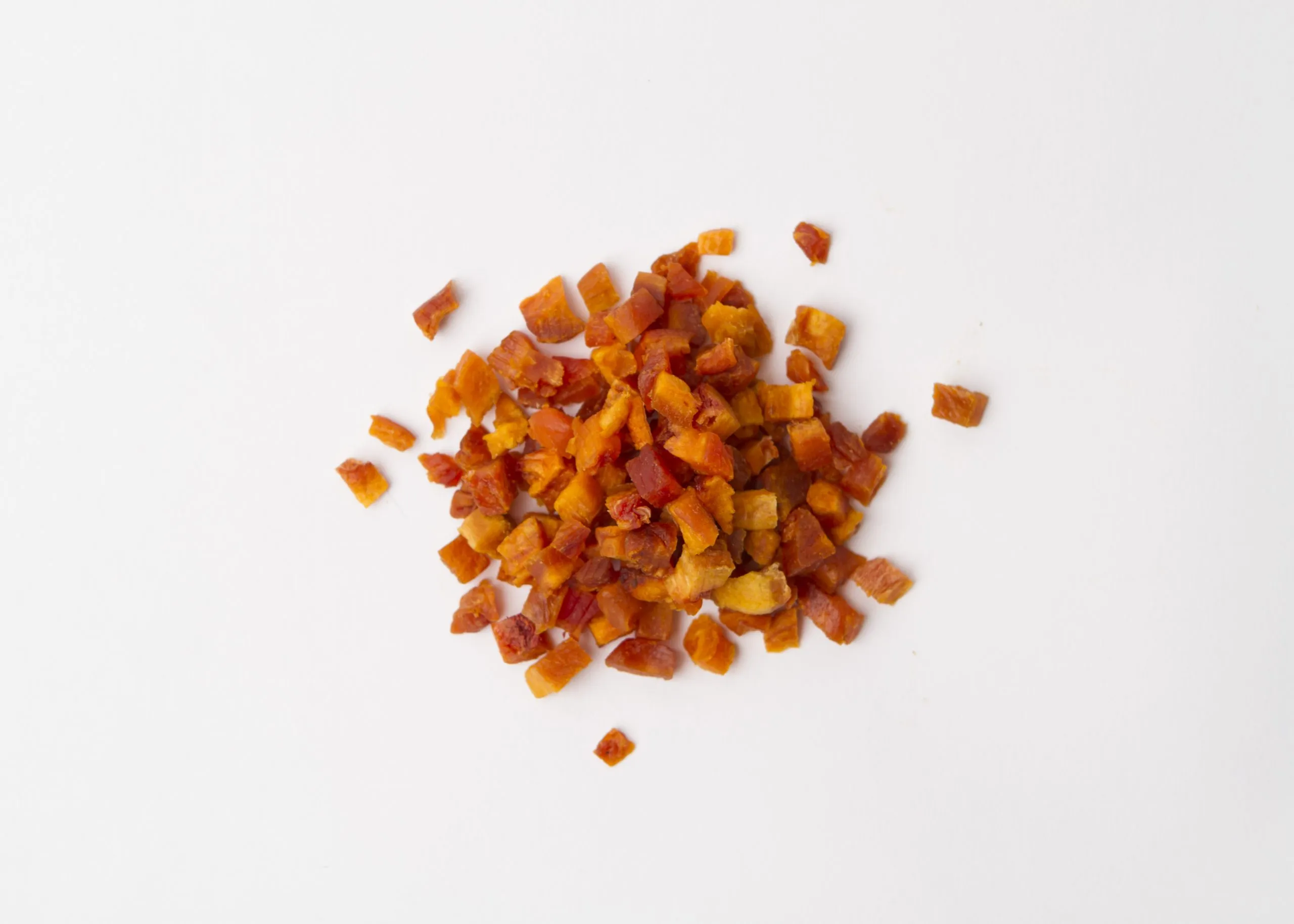 Traina® Dried Peaches diced - small pile of sun dried fruit on white background.