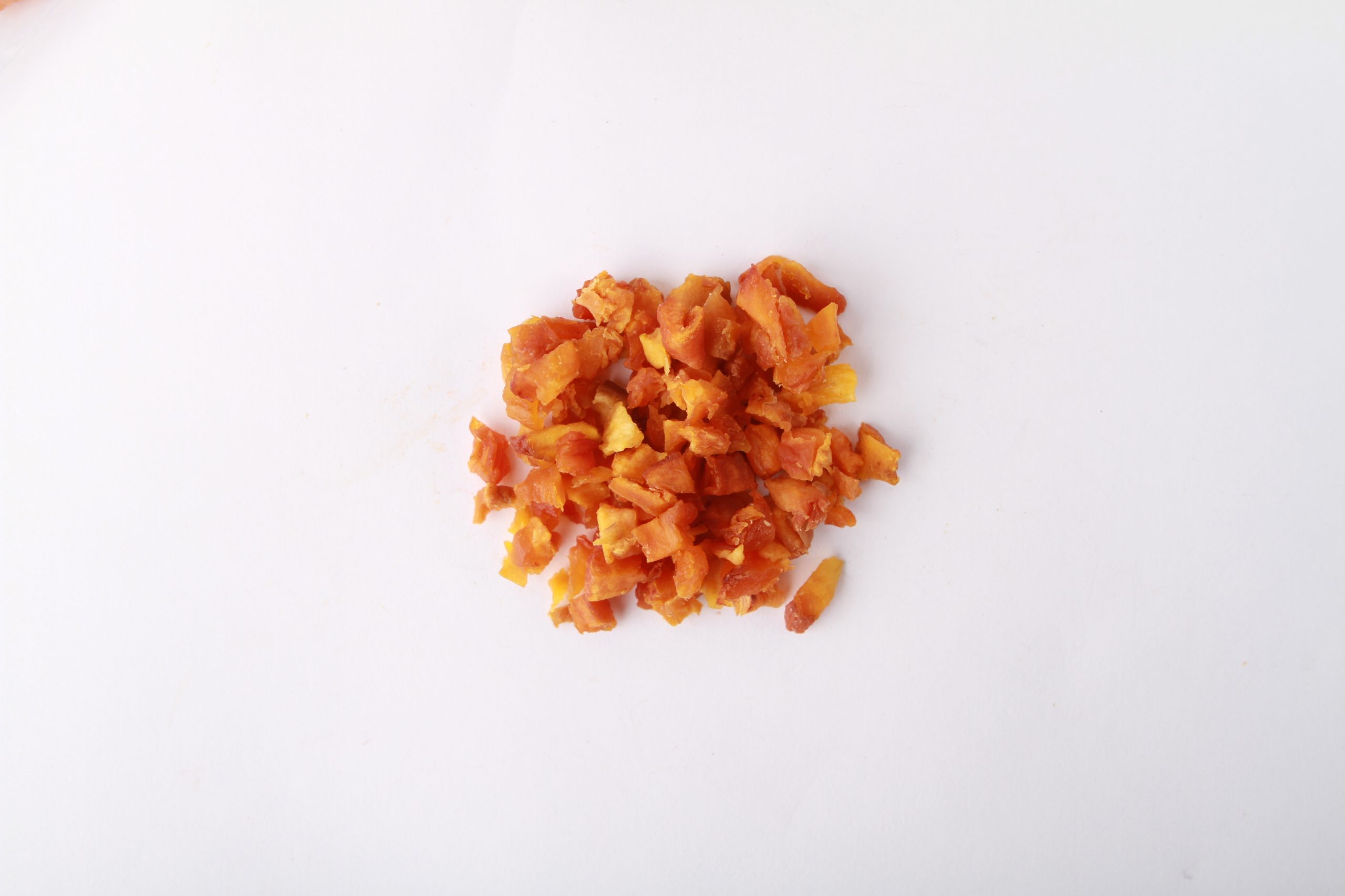 Traina® Dried Peaches double-diced - small pile of sun dried fruit on white background.